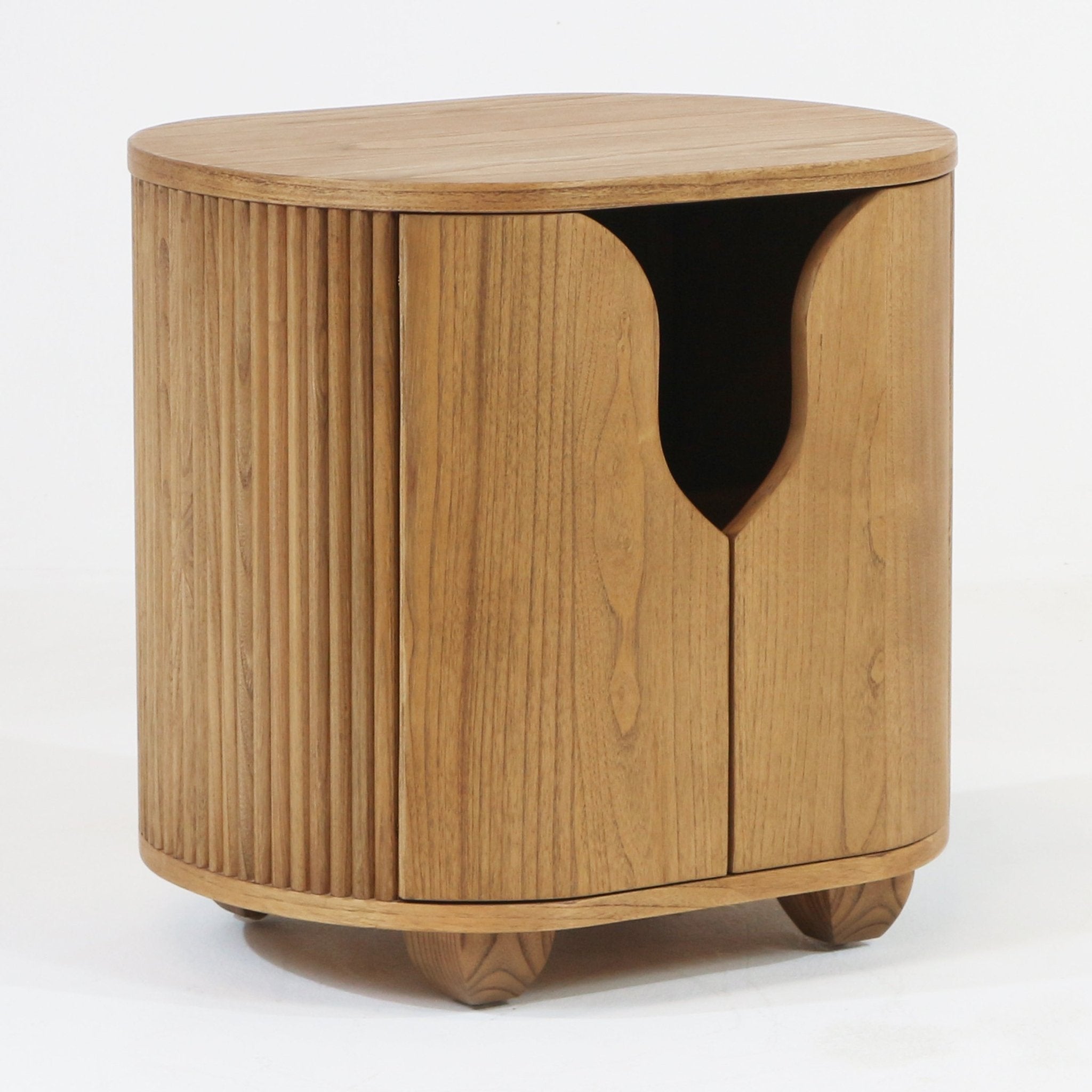 Round natural wood nightstand with a fluted side panel and curved double doors featuring a crescent-shaped cutout handle, raised on short rounded feet; modern Scandinavian bedside table in a natural wood finish.