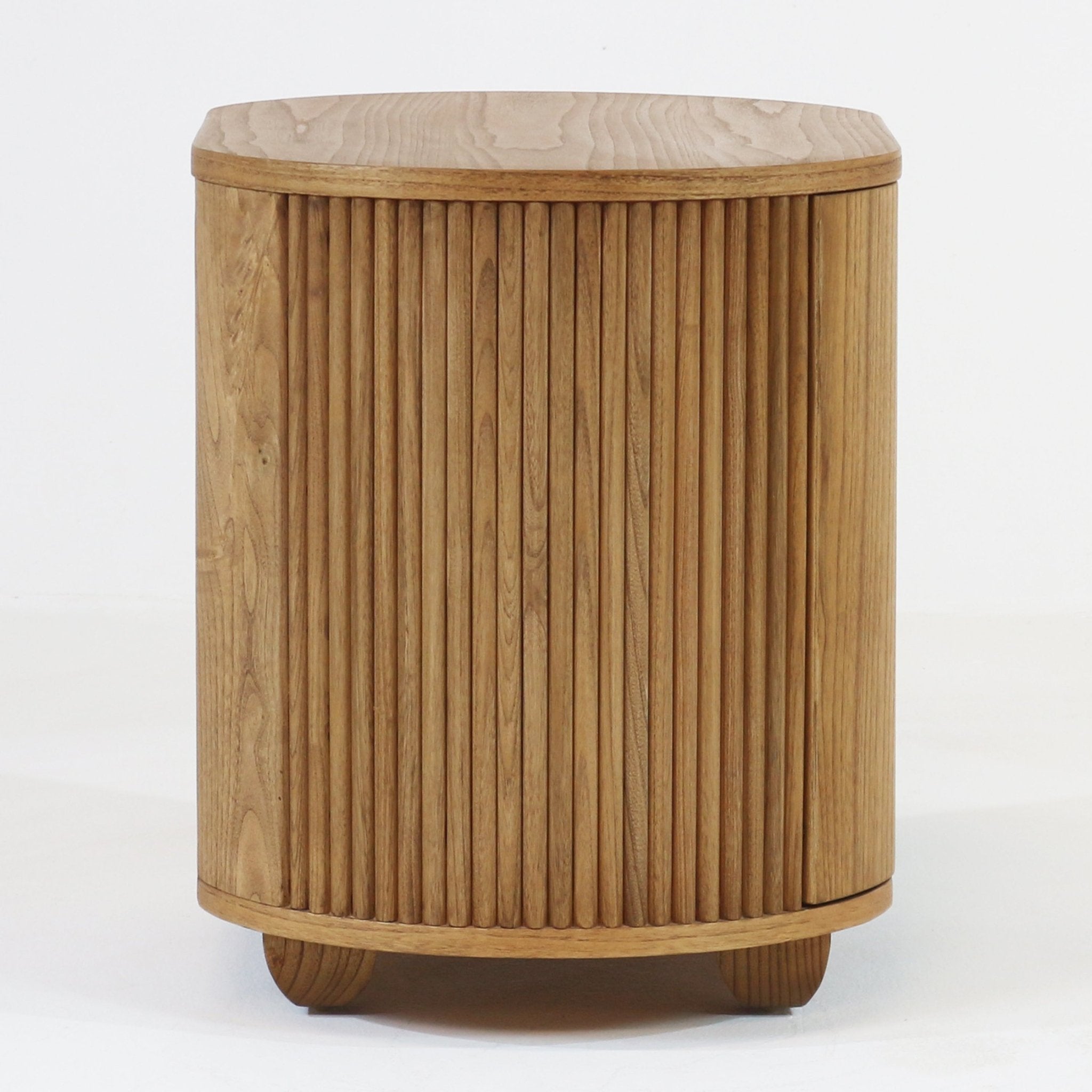 Round natural solid wood nightstand with curved front and vertical fluted slats, raised on short rounded feet, showing warm wood grain in a minimalist Scandinavian modern style.