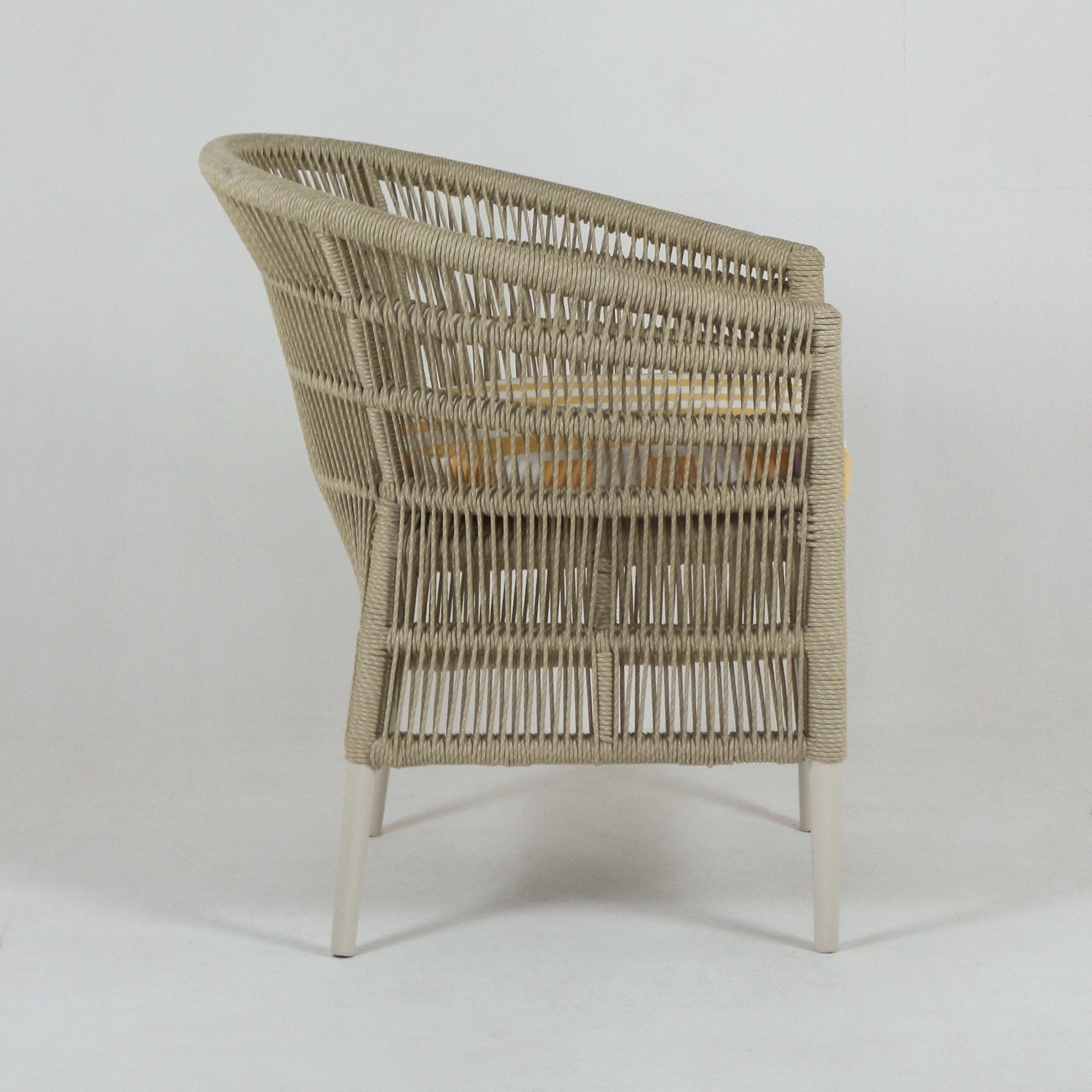 Side view of a coastal beige rope-wrapped outdoor patio chair with light metal legs and a yellow fabric seat cushion visible through the woven back.
