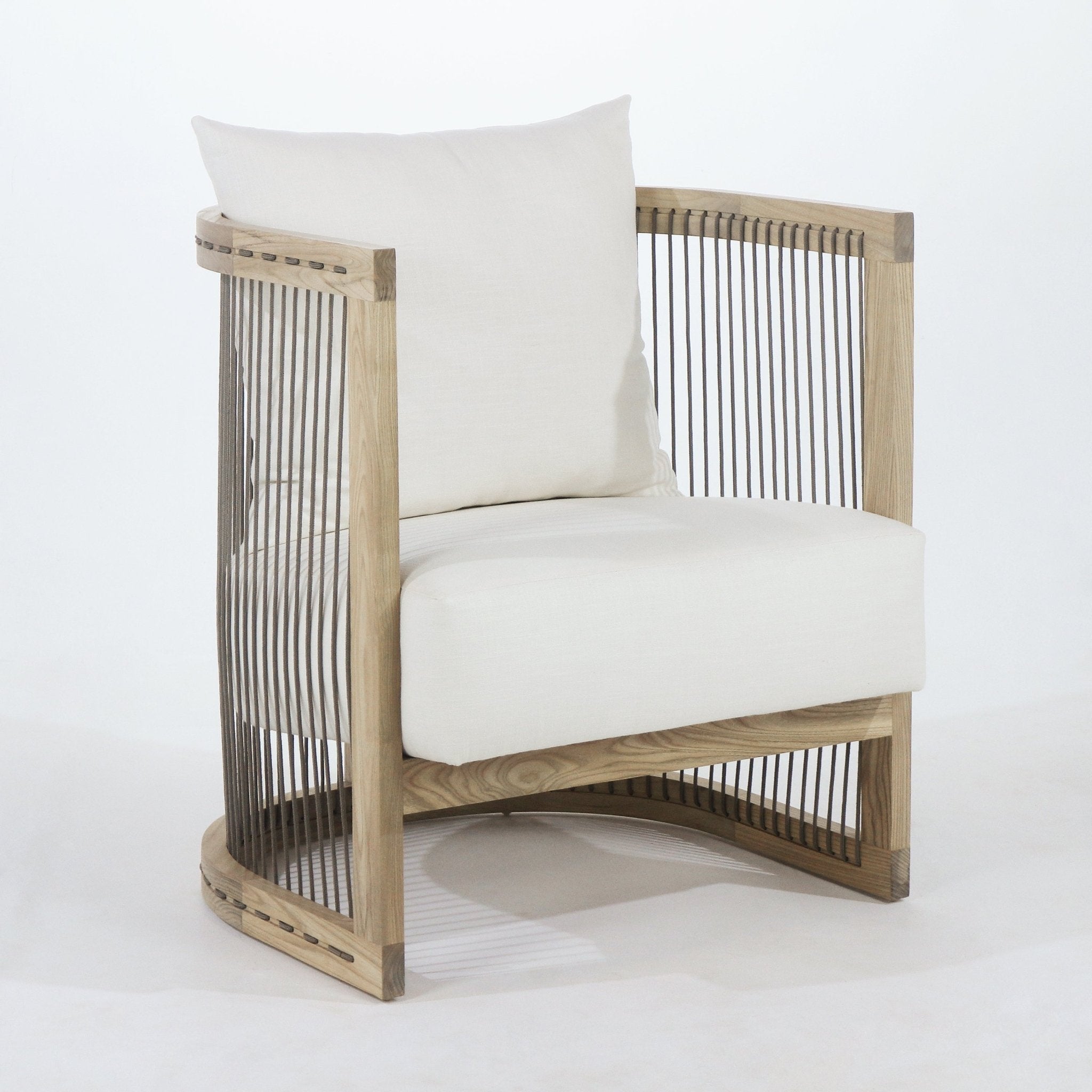 Cream fabric-upholstered dining chair with a white oak frame, curved wooden base and vertical brown rope sides, featuring a loose back cushion and a thick seat cushion in a modern Scandinavian style.