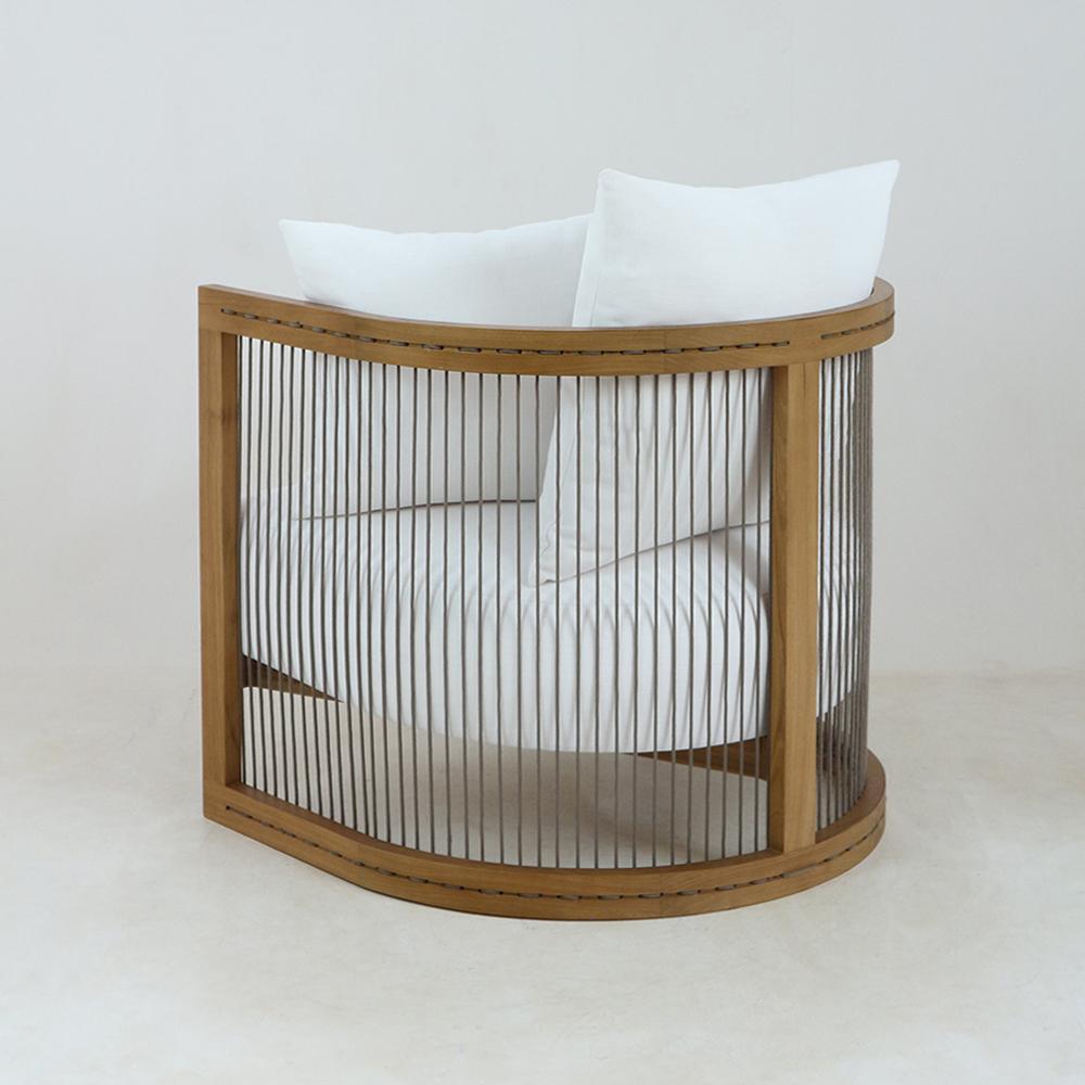 Curved modern lounge chair with natural solid wood frame and vertical woven rope slats, upholstered in white fabric with a cushioned seat and two white back pillows.