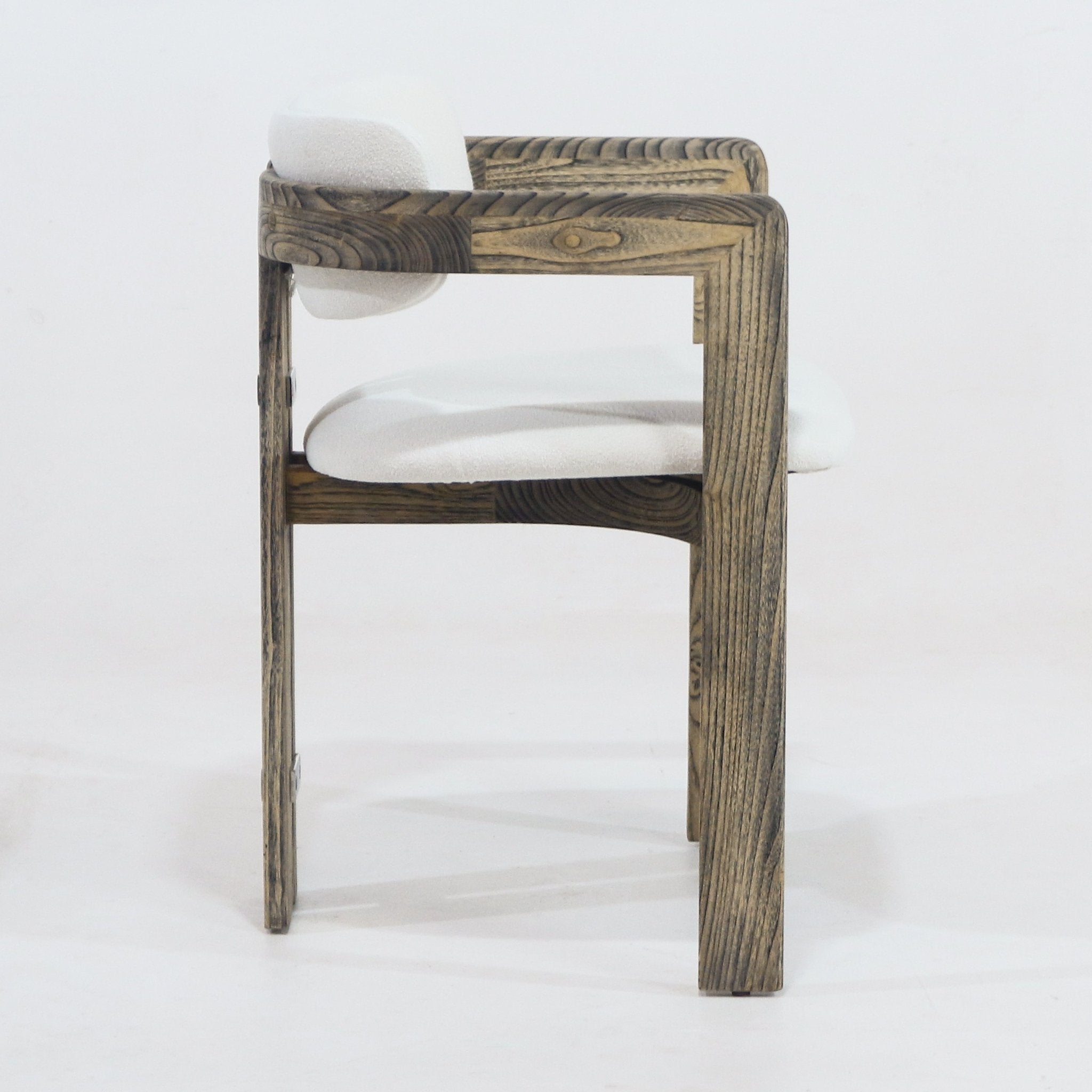 Side profile of a rustic dining chair with a brown natural wood frame and off-white boucle upholstered seat and low back, showing integrated arms and pronounced wood grain.