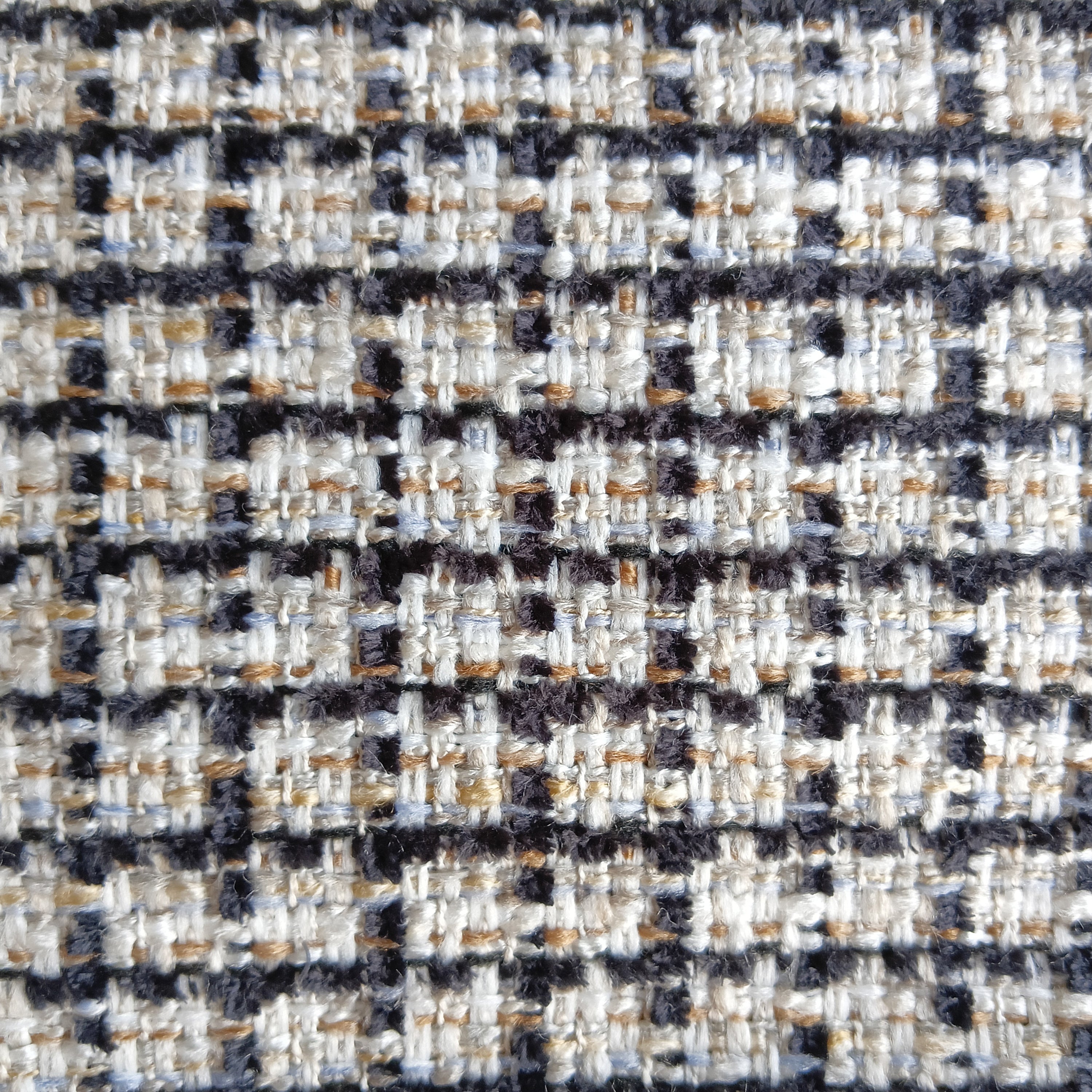 Close-up of woven upholstery fabric in cream with black grid lines and tan and light-blue accent threads, showing a textured tweed-like weave used on a mid-century modern teak dining chair.