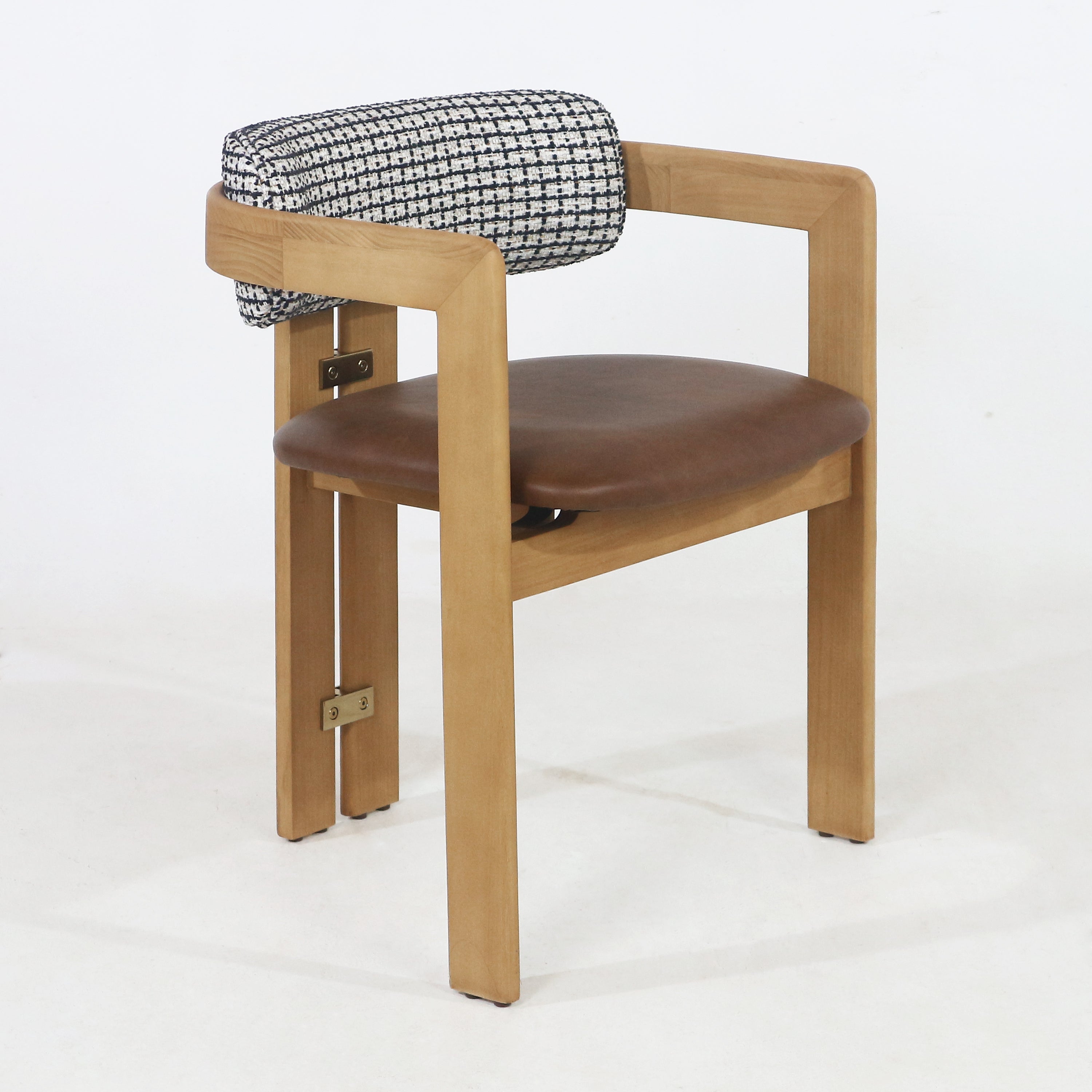 Mid-century modern teak dining chair with a curved light-teak frame, brown leather-upholstered seat and a black-and-white patterned fabric roll back cushion, accented by visible brass hardware on the rear support.