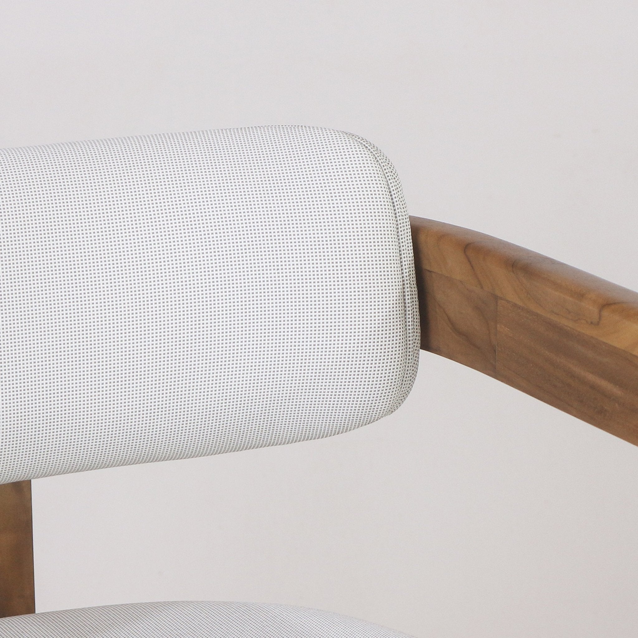 Close-up of a white textured outdoor fabric backrest paired with a curved teak arm on a contemporary outdoor bar stool.