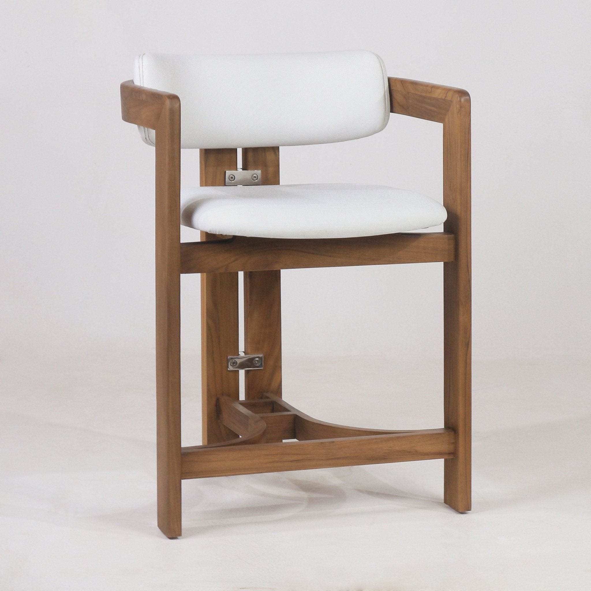 Light teak-framed bar stool with white outdoor fabric seat and rounded upholstered back, integrated wooden arms and footrest, and visible stainless mounting hardware, shown on a neutral background in a coastal contemporary style.