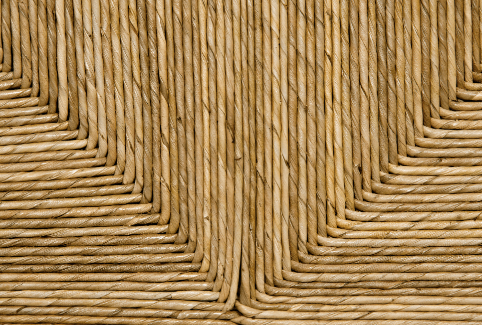 Close-up of natural seagrass weave on a solid wood sideboard panel, showing tightly twisted rope strands arranged in a geometric right-angle pattern with warm tan tones and visible fiber texture.
