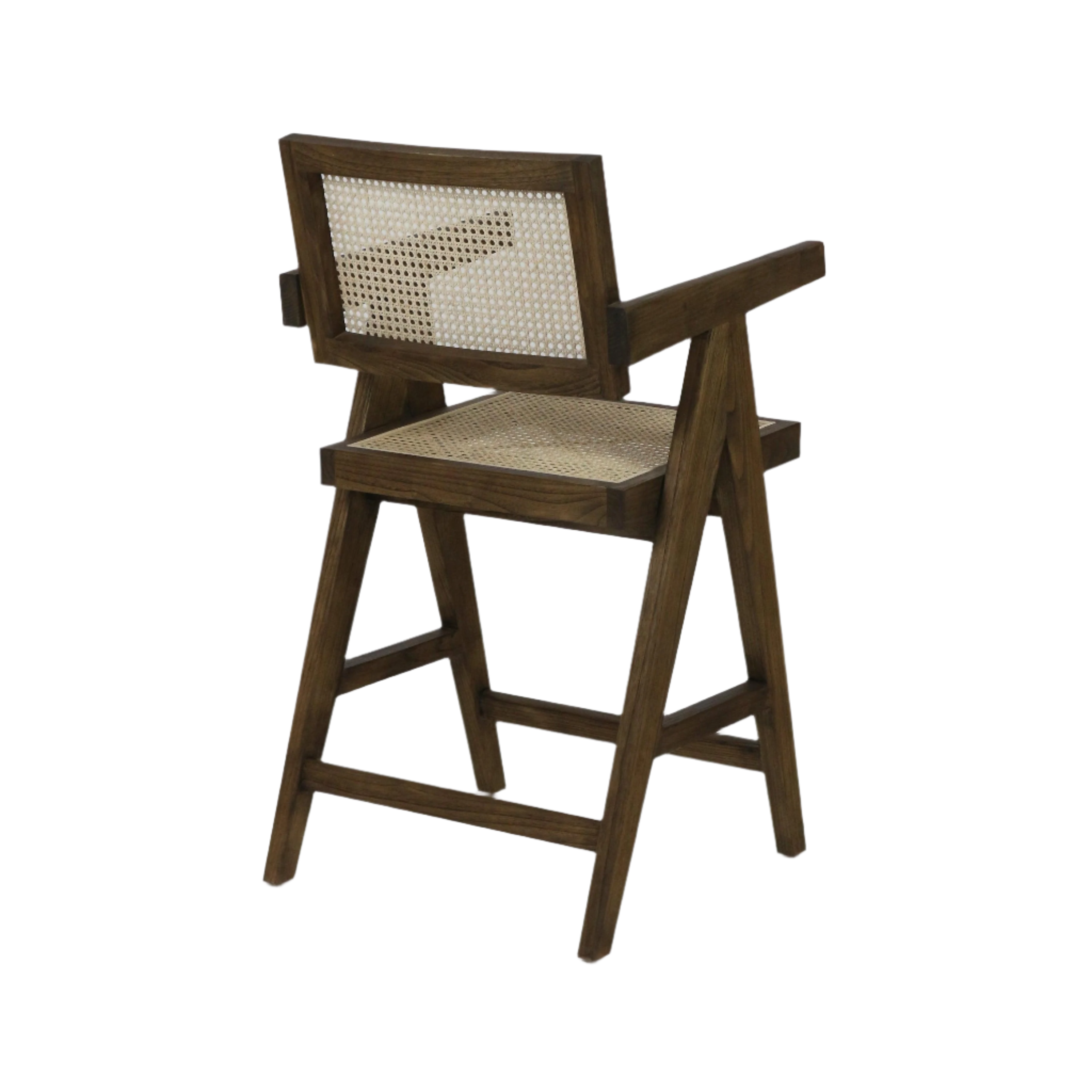 Three-quarter view of a natural wood bar stool with woven rattan seat and cane back panel, angular A-frame legs, slim wooden armrests and integrated footrest in a warm natural brown finish.