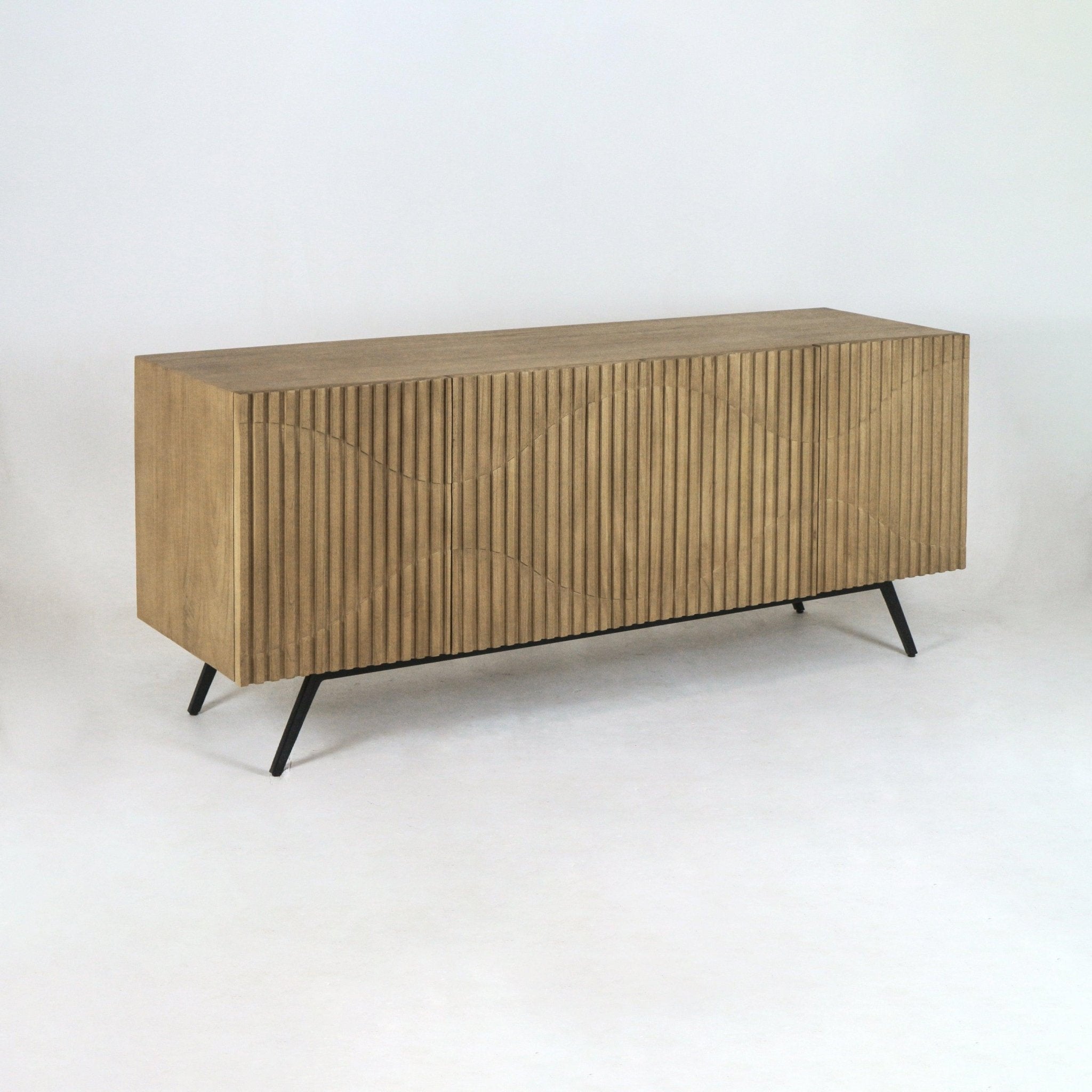 Ribbed teak sideboard with sculpted wave-front panels and angled black metal legs, shown on a white backdrop; a mid-century modern console for dining or living spaces.