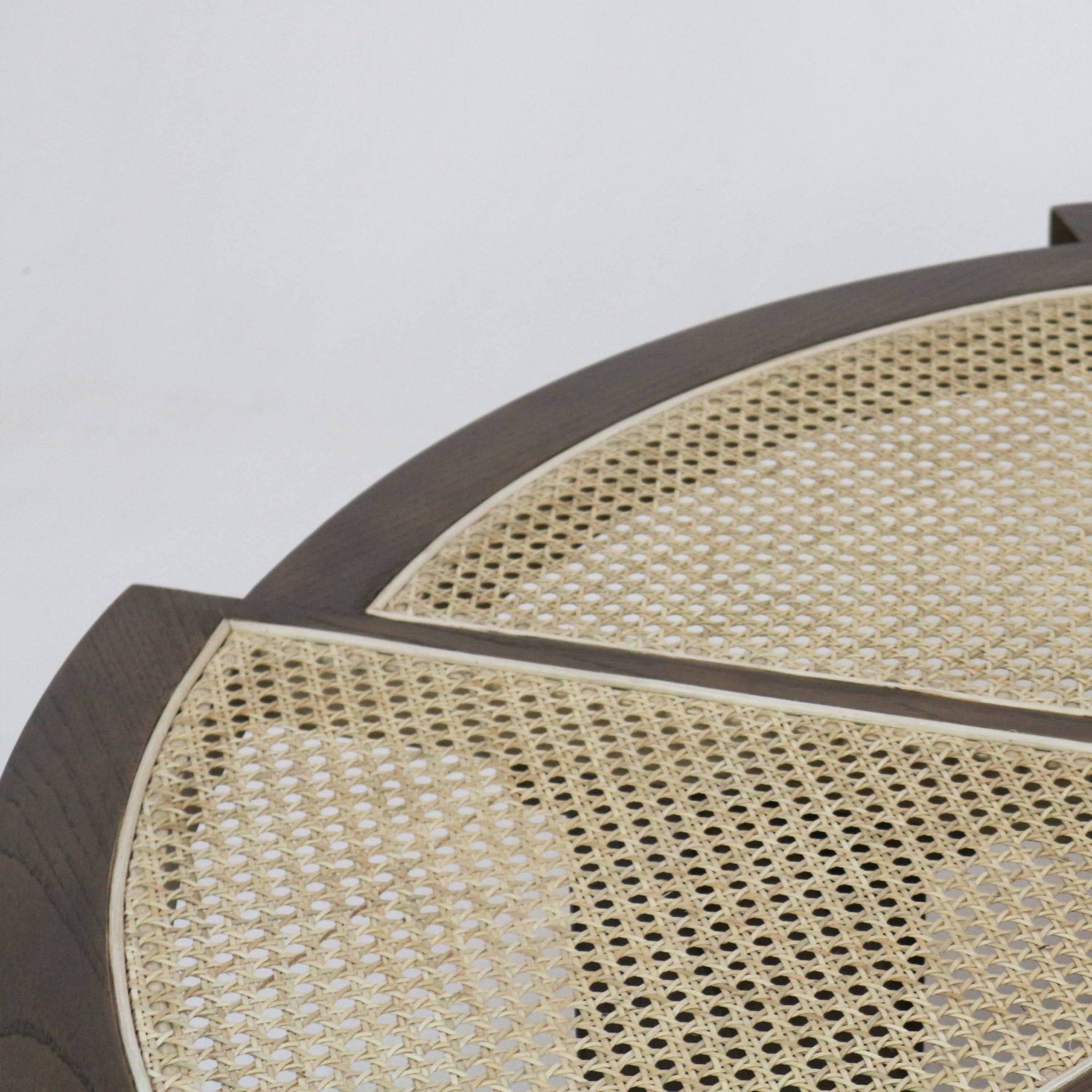 Close-up of a round coffee table top showing natural cane weave inset within a smoked-black wood frame, highlighting the woven rattan pattern and dividing wood trim in a modern mid-century style.