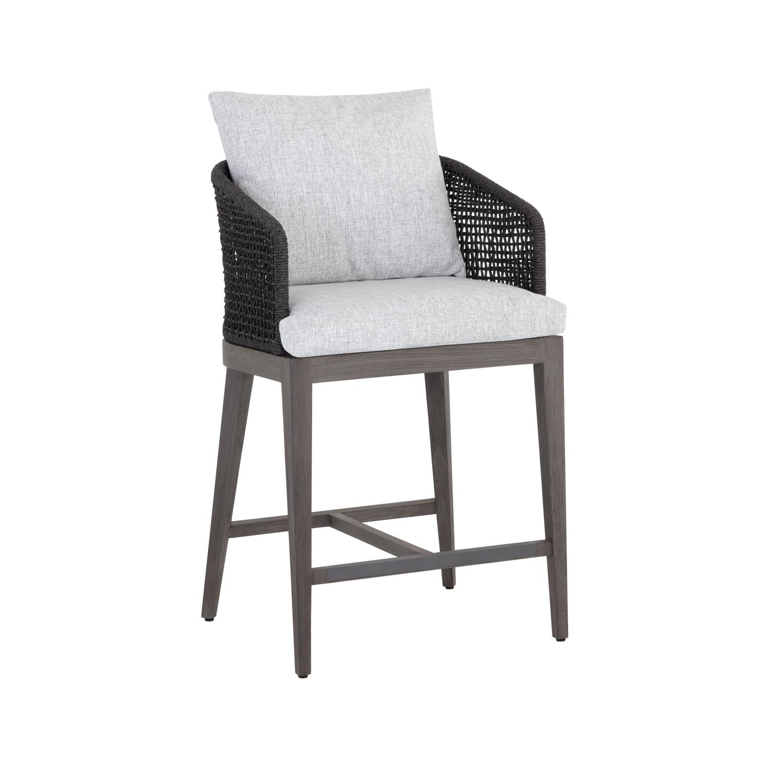 Teak outdoor bar stool with light gray fabric seat and back cushions, dark woven rope arm panels, tapered teak legs and crossbar footrest for coastal-style counter-height seating.