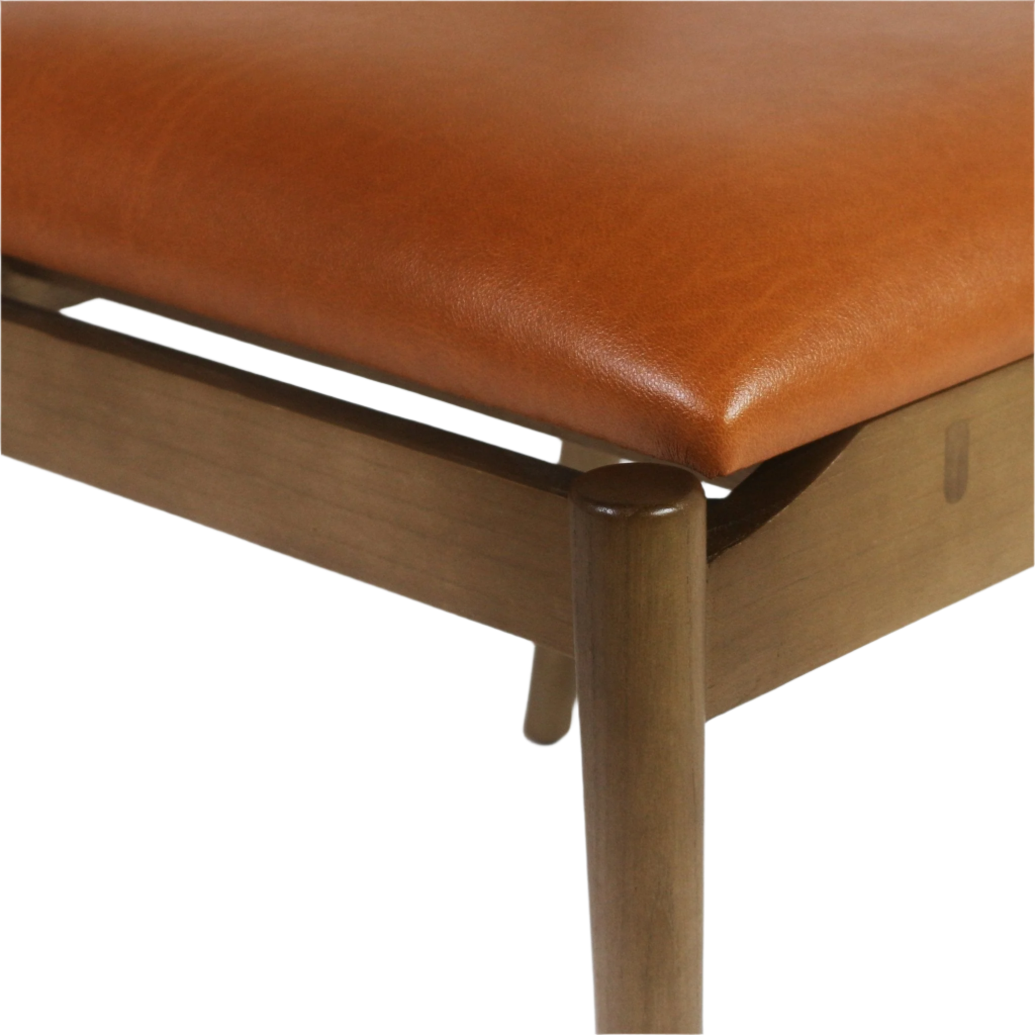 Close-up of a cognac faux leather upholstered seat corner on a natural wood frame with a rounded modern wooden leg, showing smooth leather texture and visible wood grain.