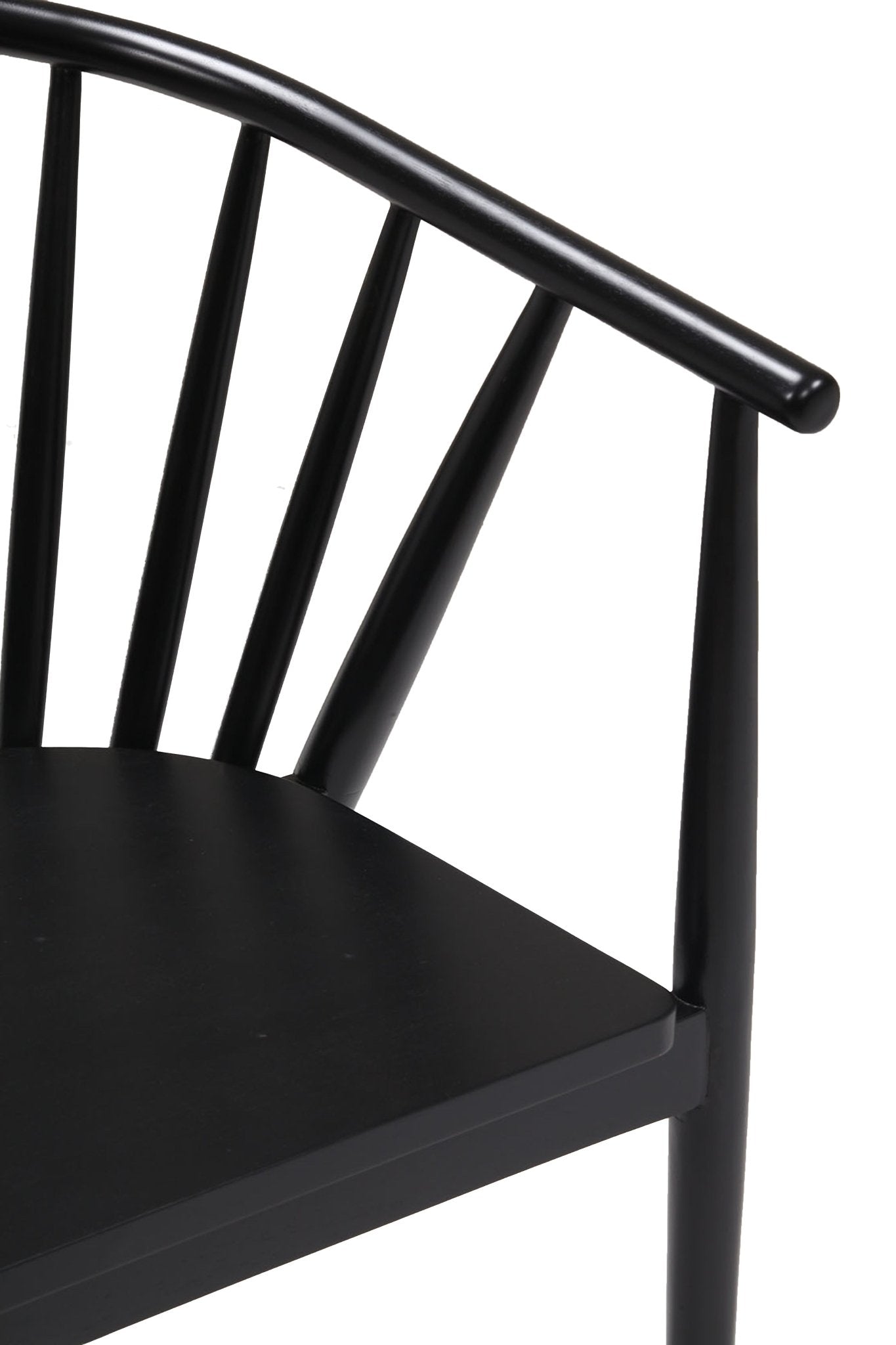 Close-up of a black-painted solid wood Shaker dining chair showing the curved top rail, vertical spindles, arm support and the seat corner.