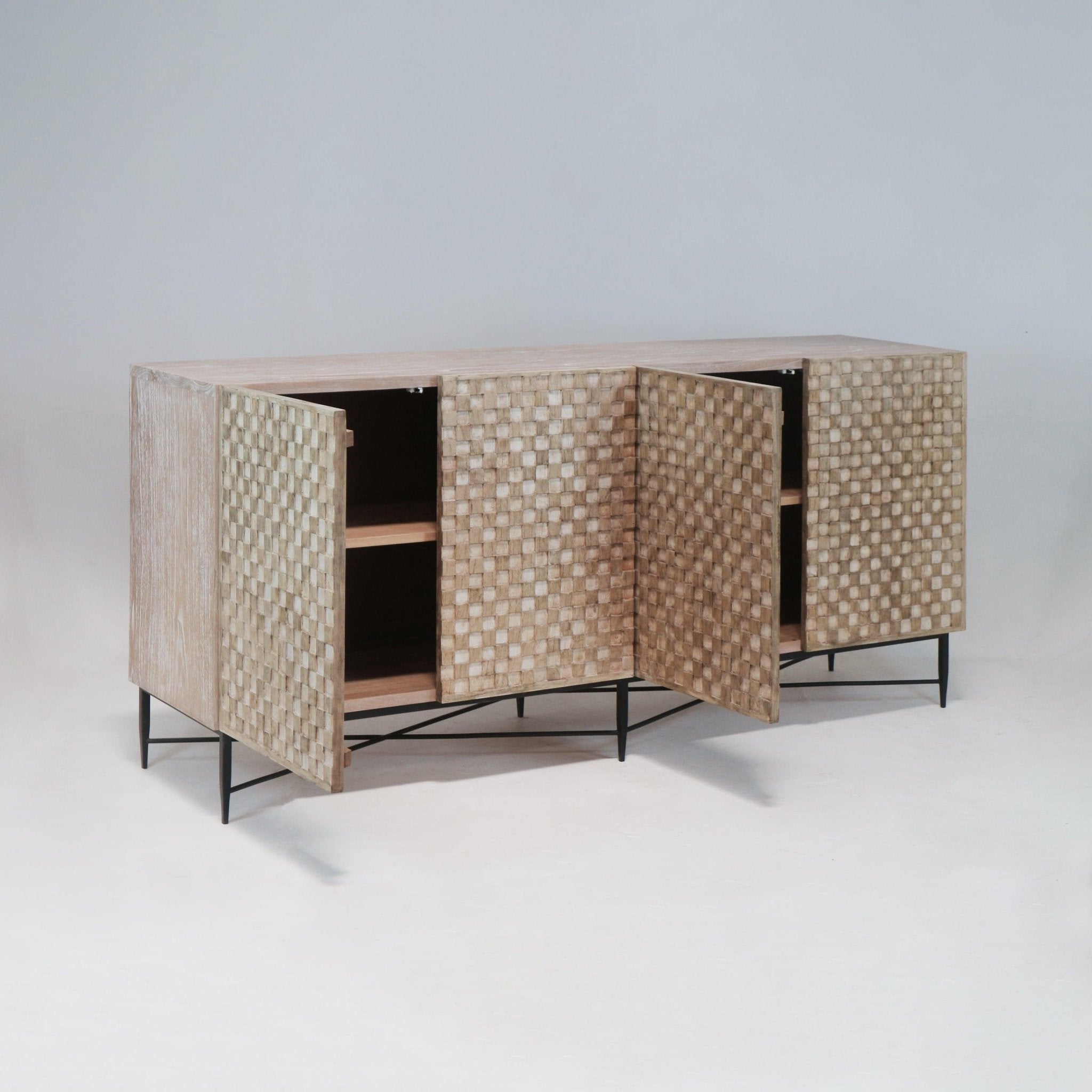 Whitewashed teak sideboard with four textured checkerboard doors, two doors open to reveal interior shelves, raised on slim black metal legs in a mid-century modern style.