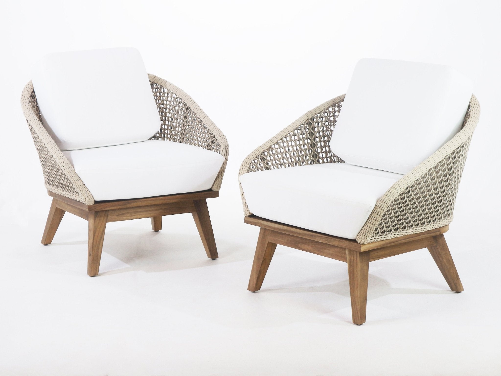 Pair of coastal-style outdoor accent chairs with natural teak legs, beige woven rope backs and white fabric seat and back cushions on a clean white background.