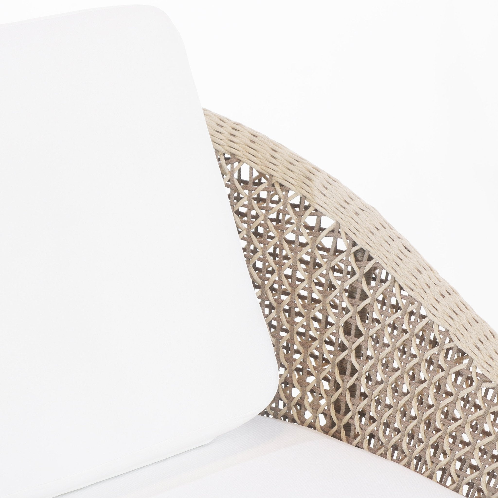 Close-up of a beige rope-woven outdoor chair back with a white fabric cushion, highlighting the braided coastal-style weave and rounded frame.