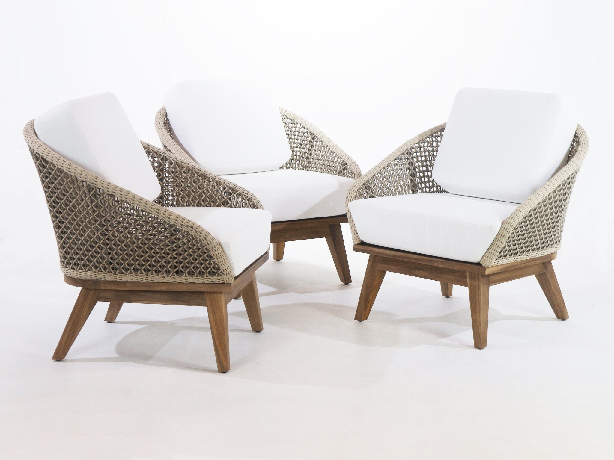 Three coastal-style outdoor accent chairs with beige rope-woven backs, white fabric cushions, and teak wood tapered legs arranged on a white background.