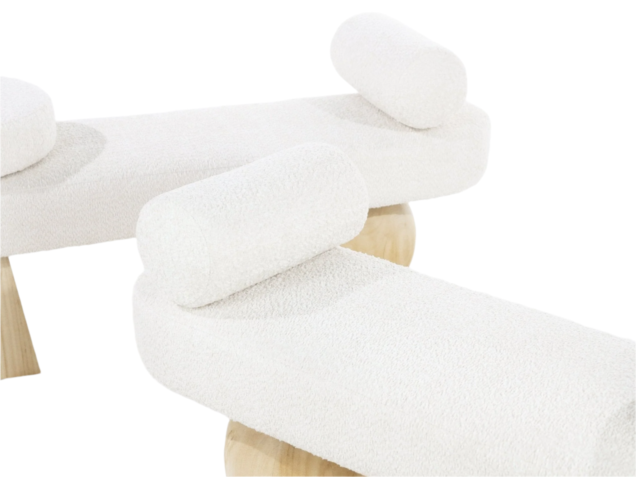 Close-up of a white boucle upholstered end-of-bed bench showing curved seat and cylindrical bolster cushions resting on natural wood pedestal legs.