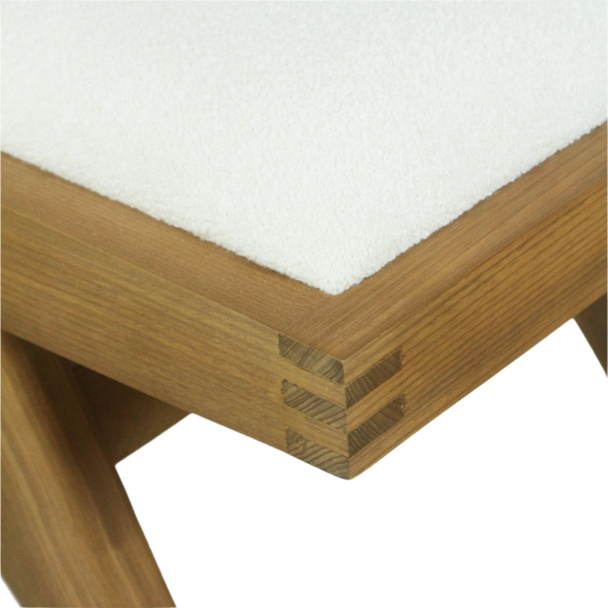 Close-up of a cream boucle upholstered seat corner on a natural ash wood frame showing the wood grain and stacked finger-joint corner detail.