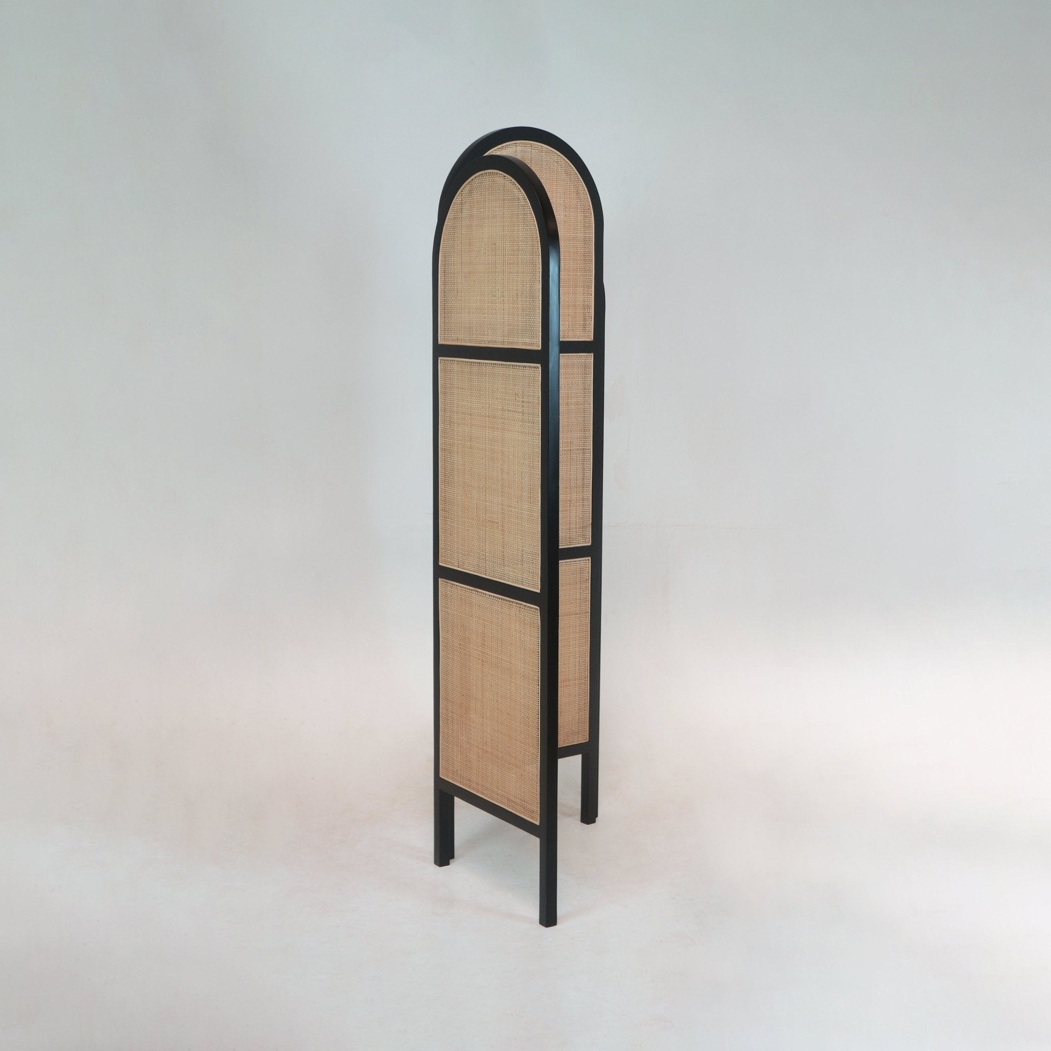 Tall freestanding room divider with arched top, black solid-wood frame and natural rattan cane panels in three vertical sections, a boho-inspired screen for living room or bedroom