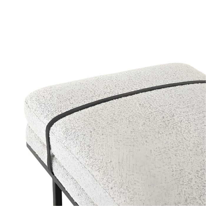 Close-up of a modern coastal end-of-bed bench corner upholstered in natural boucle fabric with contrasting black piping and a visible black metal base and leg.