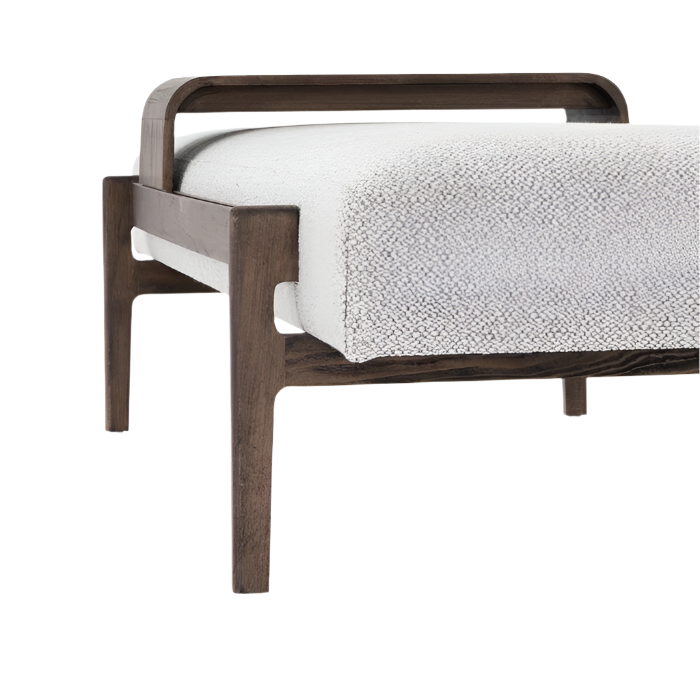 Close-up of a white boucle upholstered bench corner showing textured cushion, dark solid wood frame with tapered legs and a curved back support in a coastal-contemporary modern style.