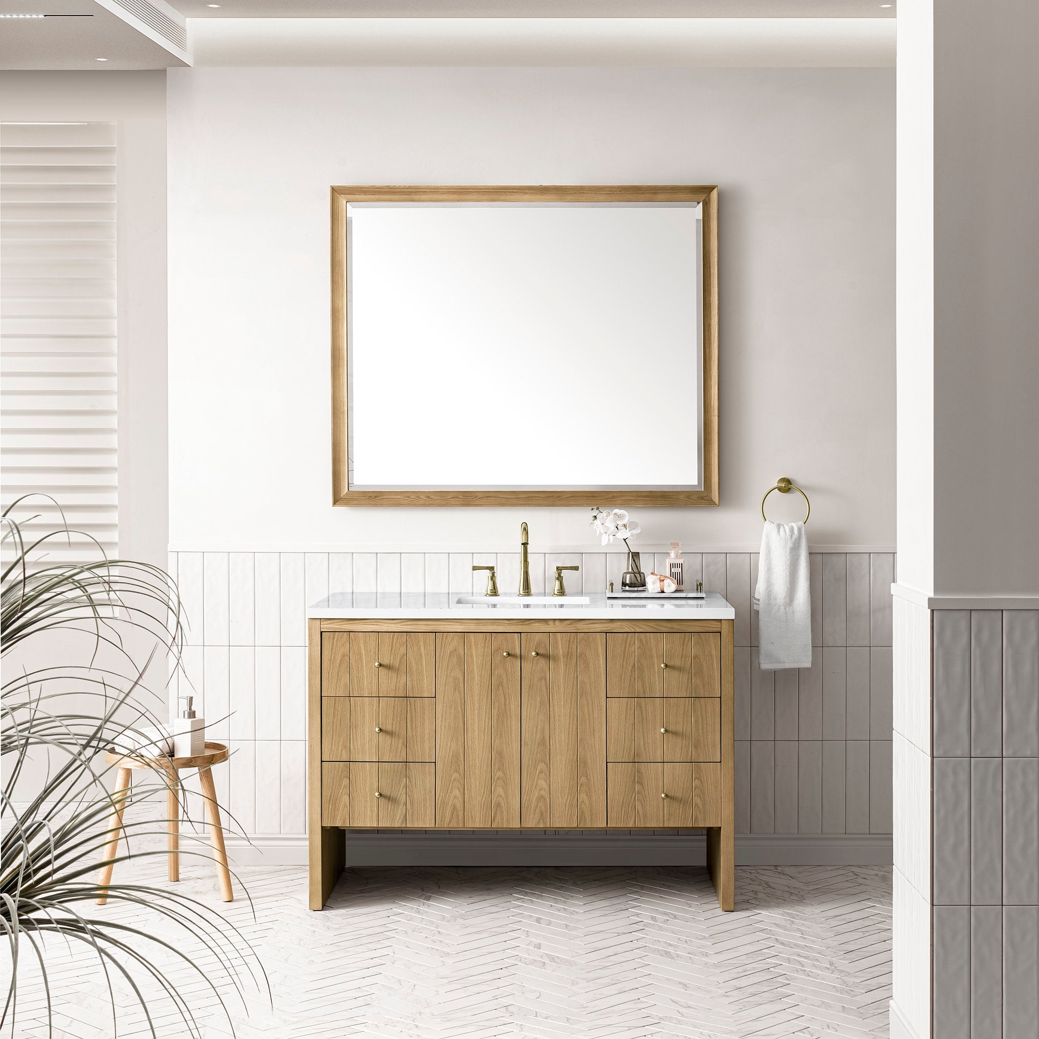 Freestanding 48-inch modern single-sink bathroom vanity in light natural oak with a stone quartz top, rectangular undermount sink, brass faucet, matching wood-framed mirror and towel ring.