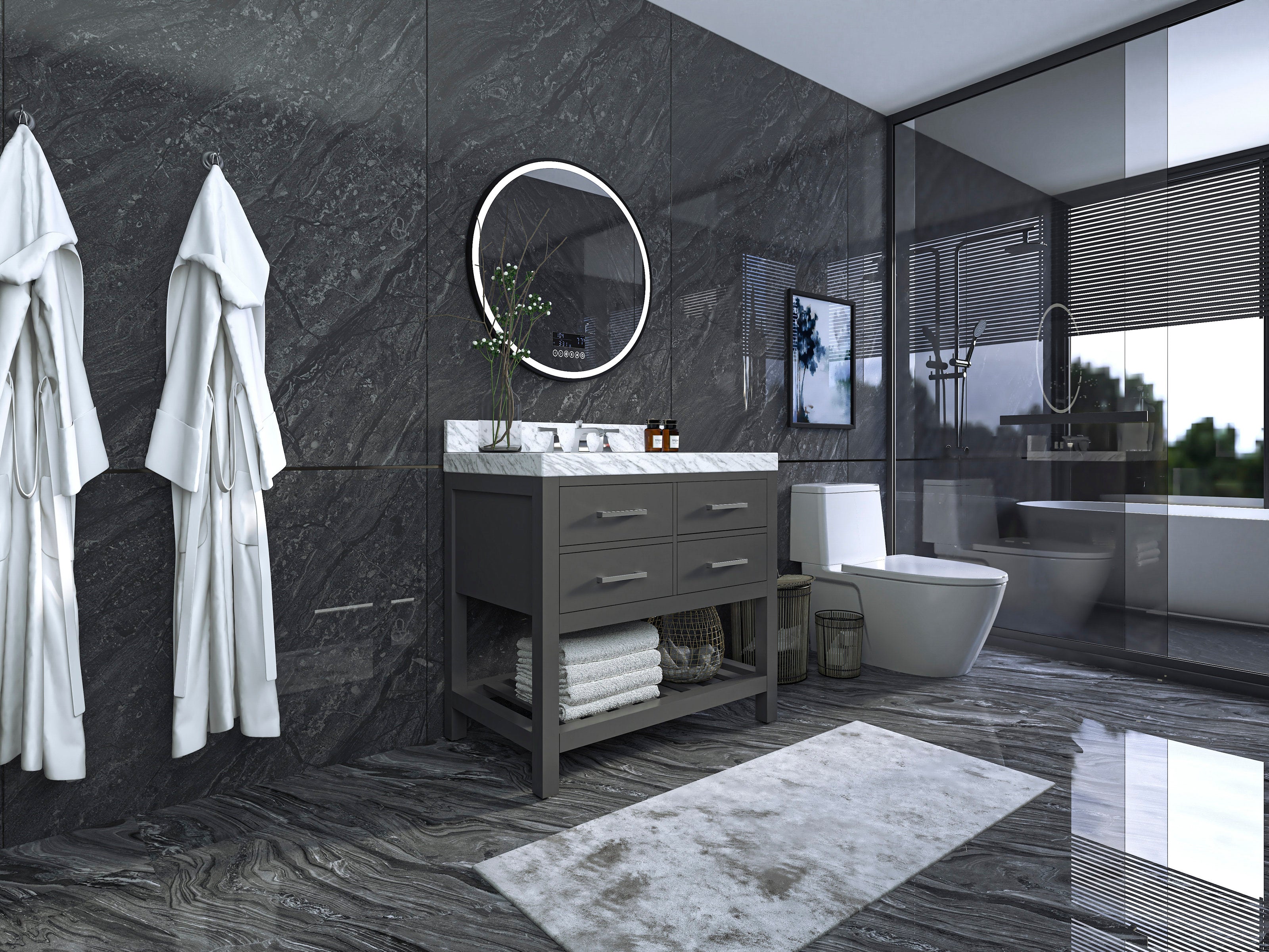 Modern solid wood gray bathroom vanity with white stone marble top, round mirror, chrome faucet and open lower shelf with folded towels, set against dark stone walls and a glass shower enclosure.