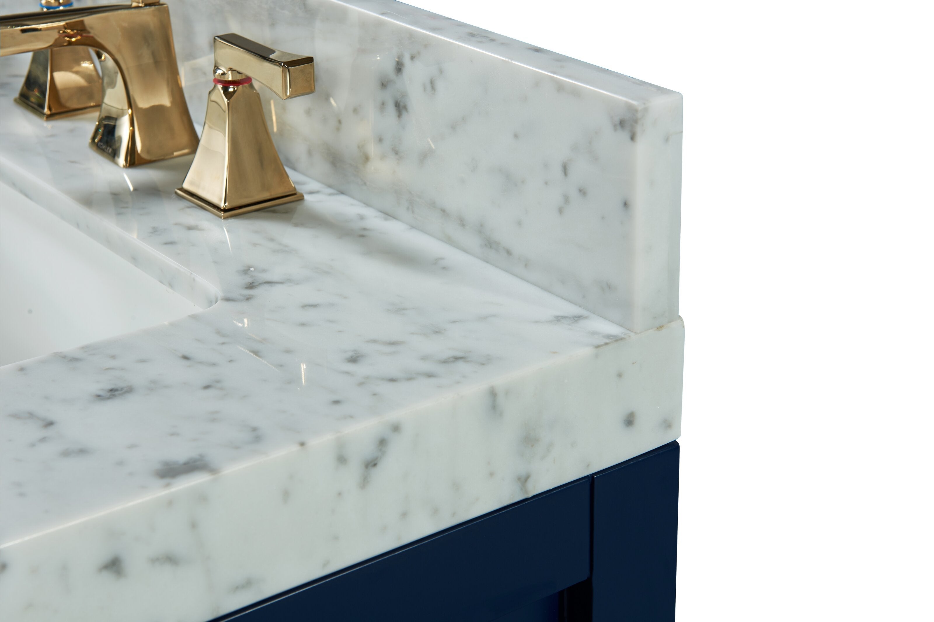 Close-up of a white stone marble countertop and matching backsplash with gray veining, modern brass faucet handles, and the corner of a dark navy solid wood bathroom vanity.