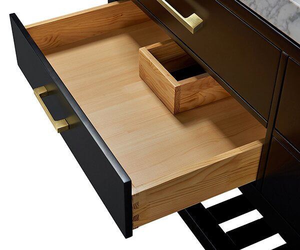 Open drawer of a black contemporary single-sink vanity showing a natural solid wood interior with a small wooden organizer, brass drawer pull, and a stone marble countertop edge.