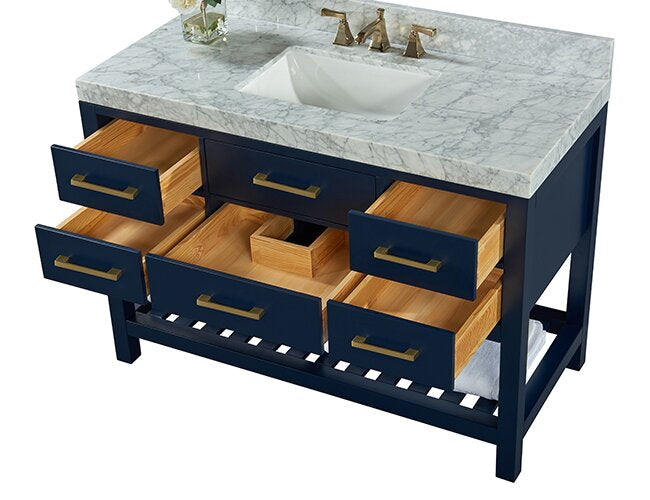 48-inch freestanding bathroom vanity with stone marble top and integrated white ceramic sink, navy solid-wood base with six open drawers showing natural wood interiors, brushed-gold pulls and faucet, and a slatted lower shelf with towel.