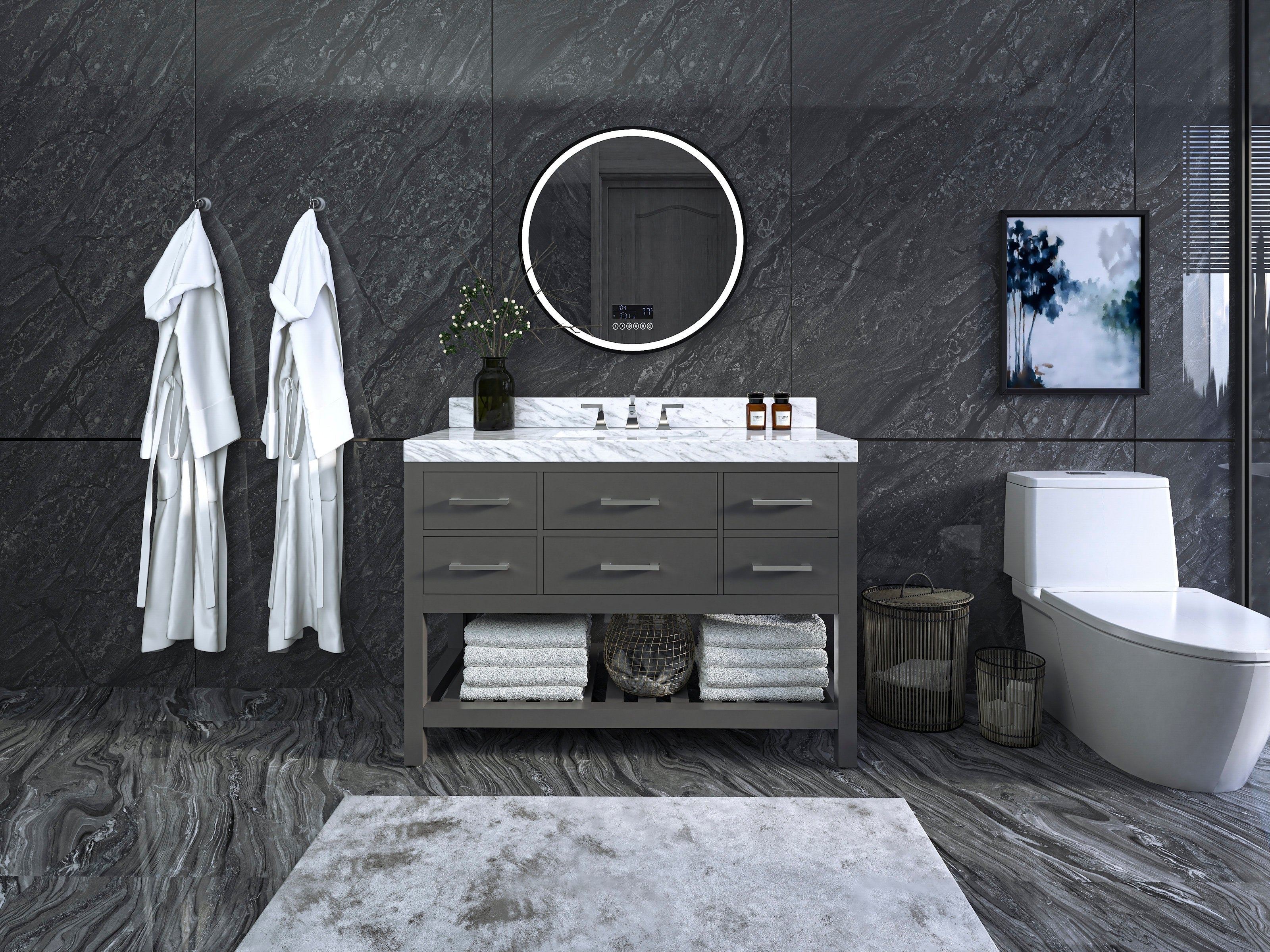 48-inch modern solid-wood bathroom vanity in stone gray with a white marble top and single sink, round backlit mirror above, open shelf with folded towels, robes on wall hooks and a white toilet to the right.