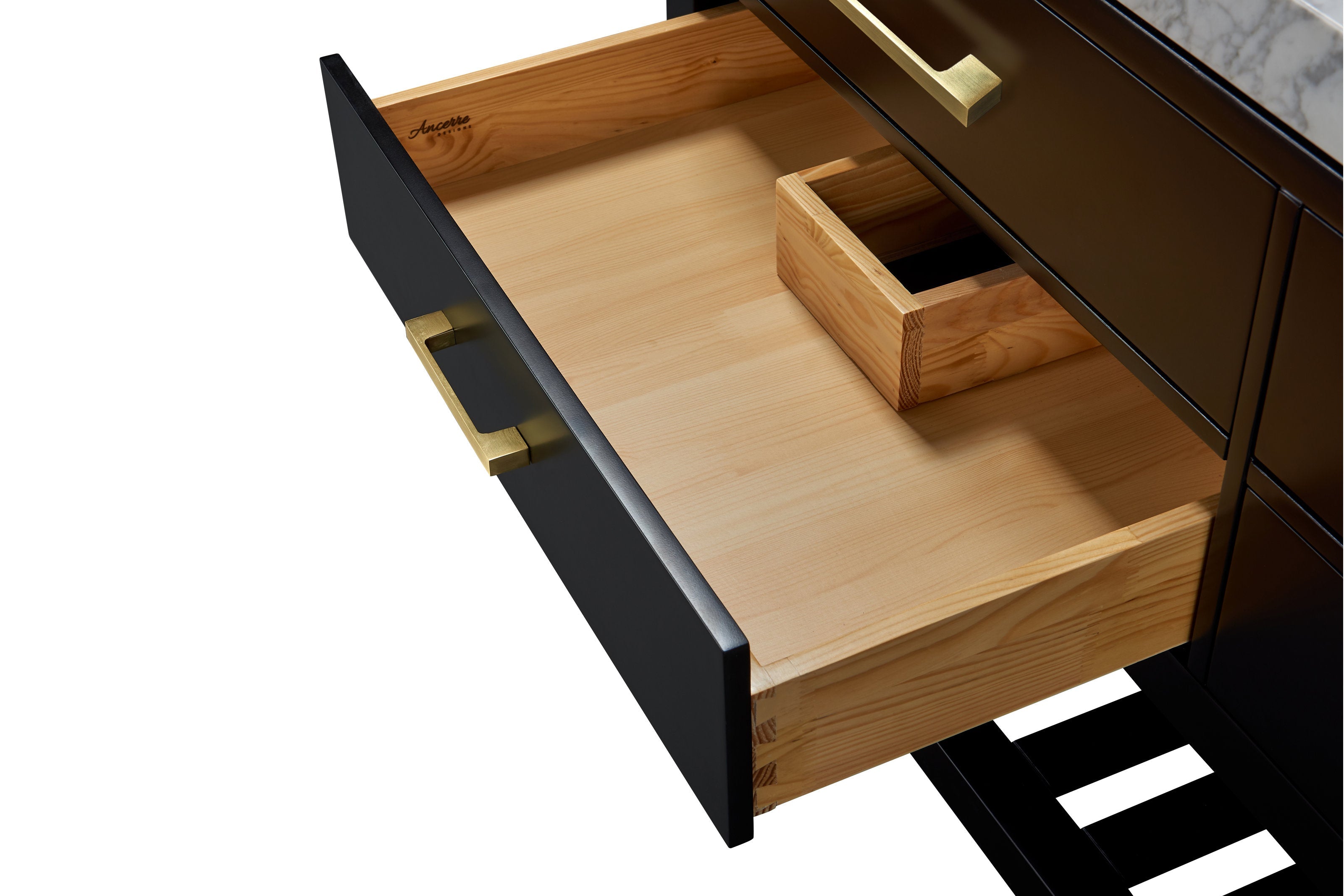 Open black bathroom vanity drawer showing natural solid wood interior with visible dovetail joints, a removable wood organizer, marble countertop edge above, and a brushed gold brass drawer handle.