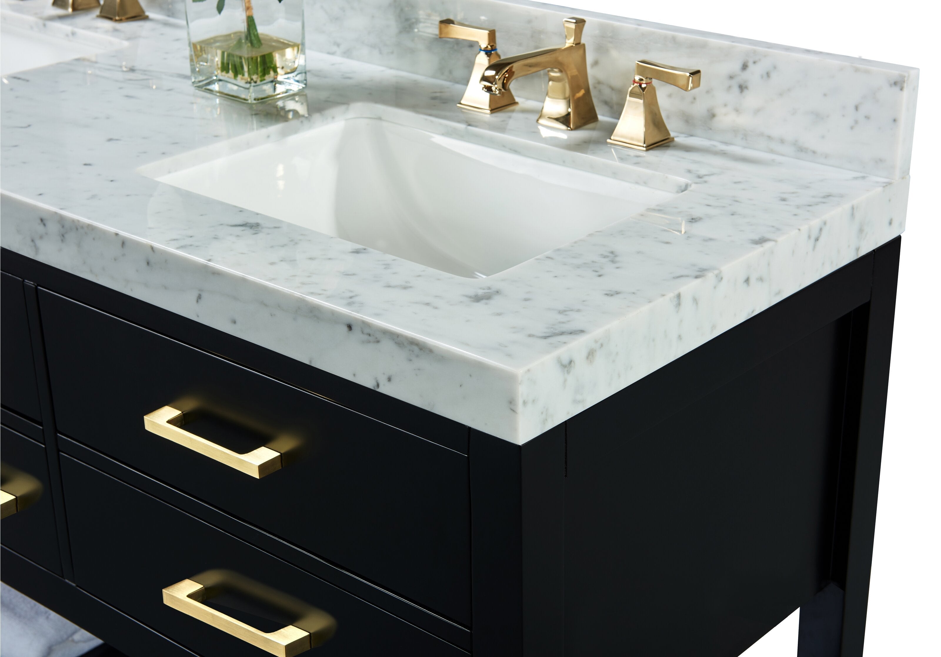 Close-up of a modern black solid-wood vanity with a white undermount ceramic sink set into a stone marble top and backsplash, featuring a brushed gold faucet and matching rectangular gold drawer pulls.