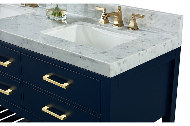 Close-up of a navy solid-wood bathroom vanity with a white stone marble countertop and backsplash, integrated rectangular ceramic sink, and polished gold faucets with matching gold drawer pulls.