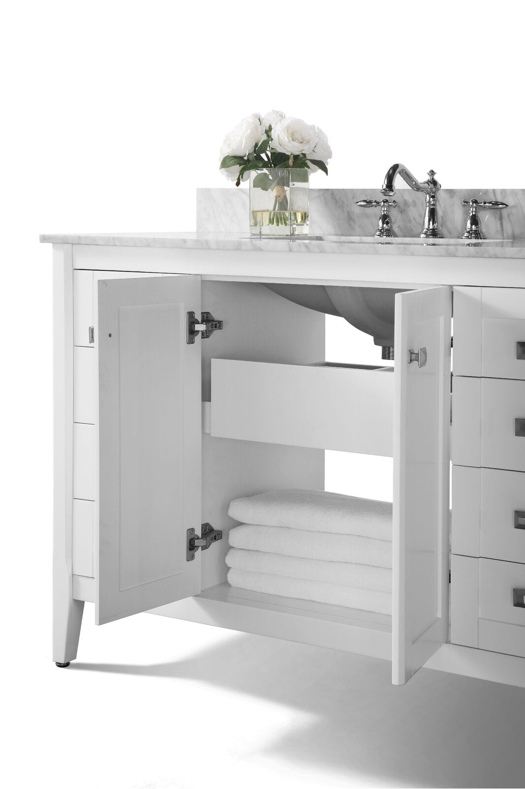 Modern white solid-wood bathroom vanity with a stone marble top and chrome faucet; center cabinet doors open to reveal a storage drawer and stacked white towels, with a glass vase of white roses on the countertop.