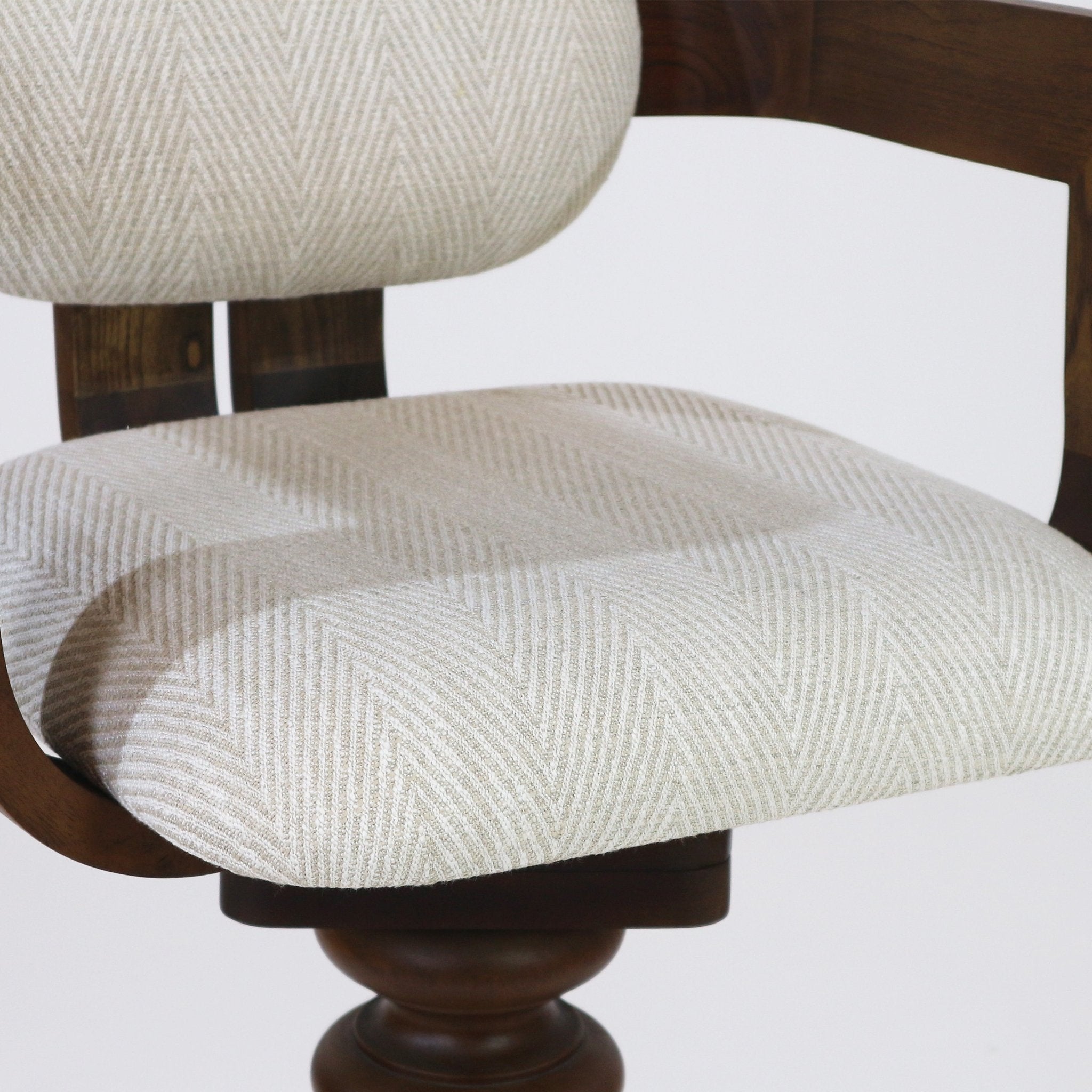 Close-up of a beige herringbone-upholstered bar stool seat and matching backrest on a dark natural wood swivel base, highlighting the cushioned fabric texture and curved wooden supports.