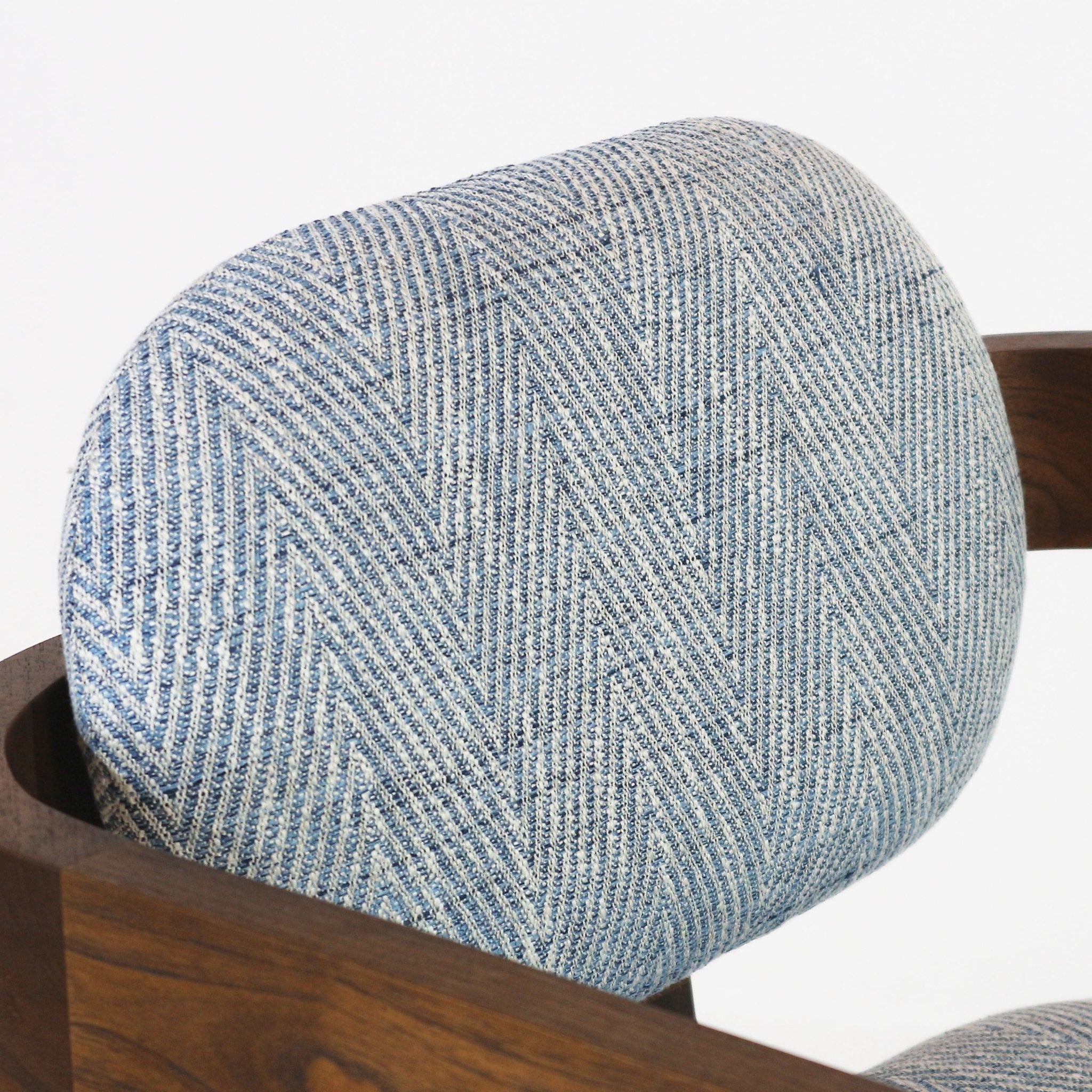 Close-up of a light‑blue and white woven chevron fabric back cushion on a modern swivel bar stool, paired with a dark natural wood frame.