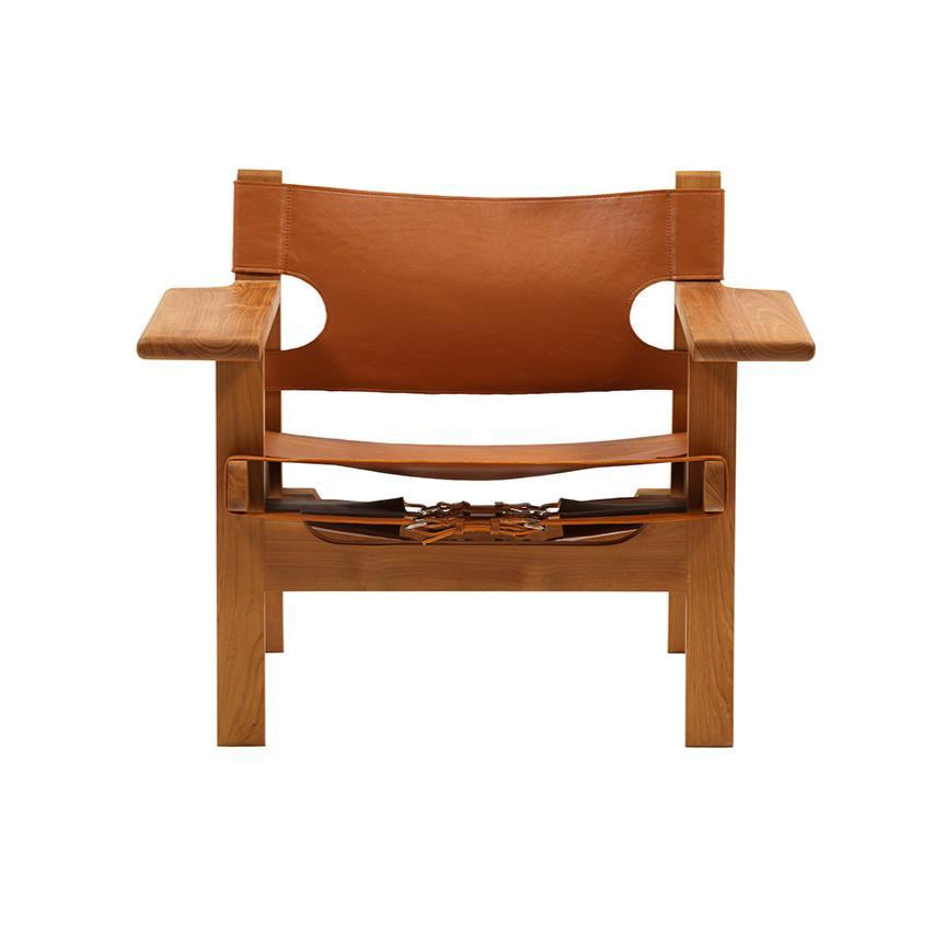 Front view of a mid-century modern teak armchair with a solid teak frame, wide flat armrests and tan leather sling seat and back secured by visible leather straps and buckles.