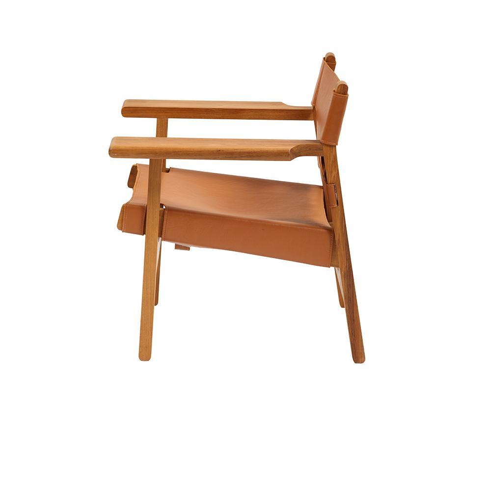 Side view of a mid-century modern armchair with a teak frame and tan leather sling seat and back, featuring flat wooden arms and exposed solid teak legs on a white background.