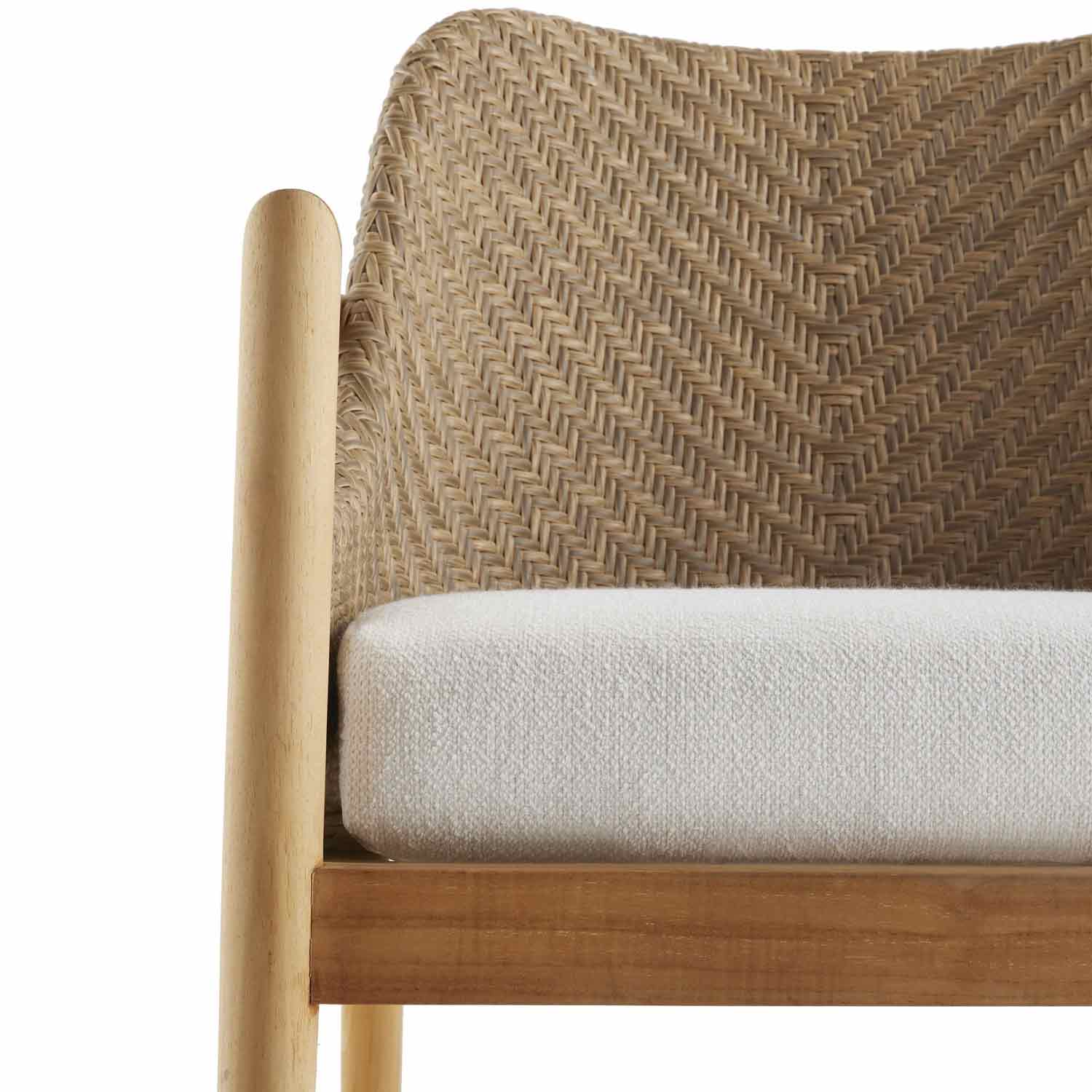 Close-up of a coastal teak outdoor dining chair showing a natural teak frame with rounded arm post, woven wicker herringbone back and a neutral off-white textured fabric seat cushion.