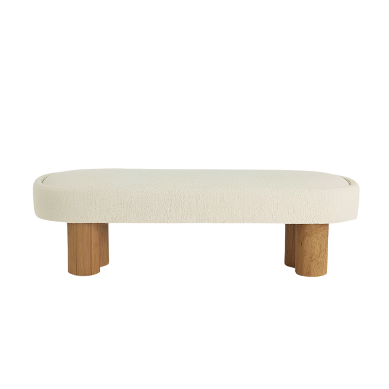 End-of-bed bench upholstered in natural boucle fabric with a rounded rectangular seat and thick cylindrical natural wood legs, shown on a white background.