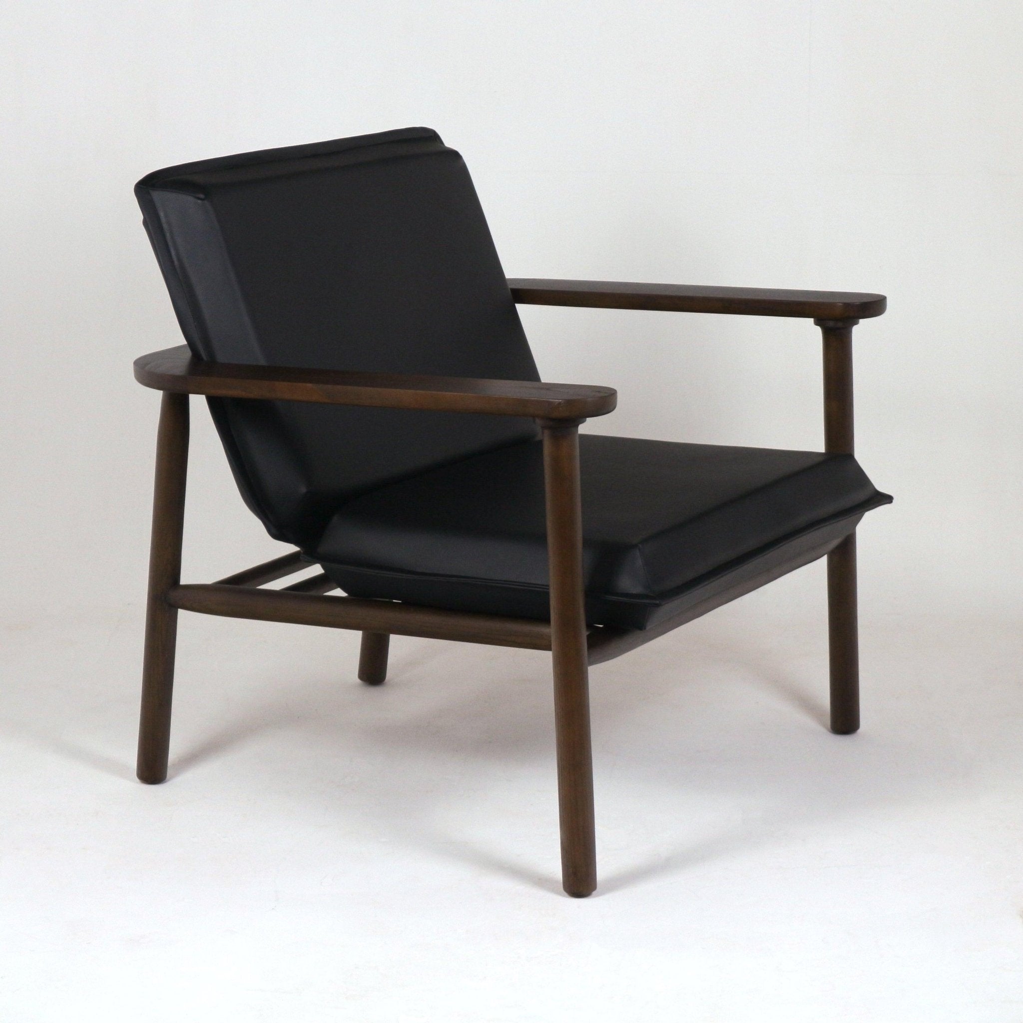 Midcentury-style lounge chair with black faux leather seat and angled cushioned back set in a warm brown solid wood frame with rounded arms and tapered legs.