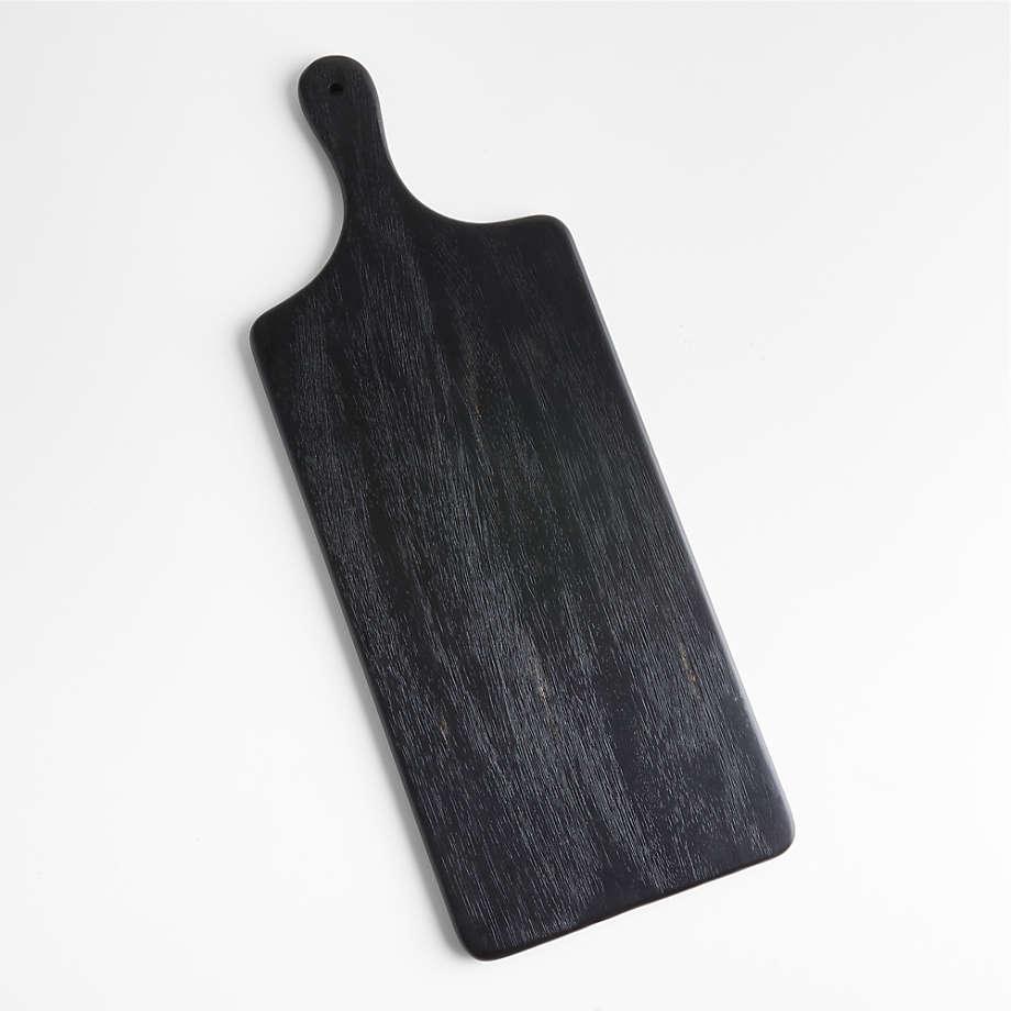 Black teak paddle-style cutting and butter board with rounded handle and visible wood grain, shown on a white background.