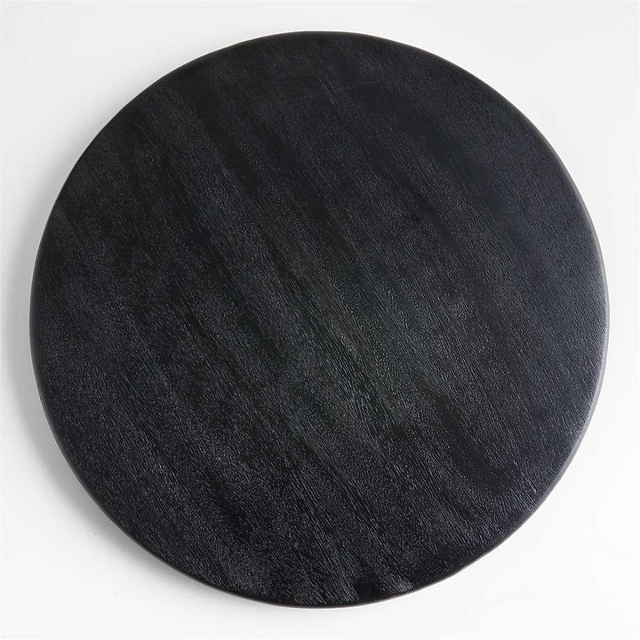Top-down view of a round black teak butter board made from solid wood with visible grain on a white background
