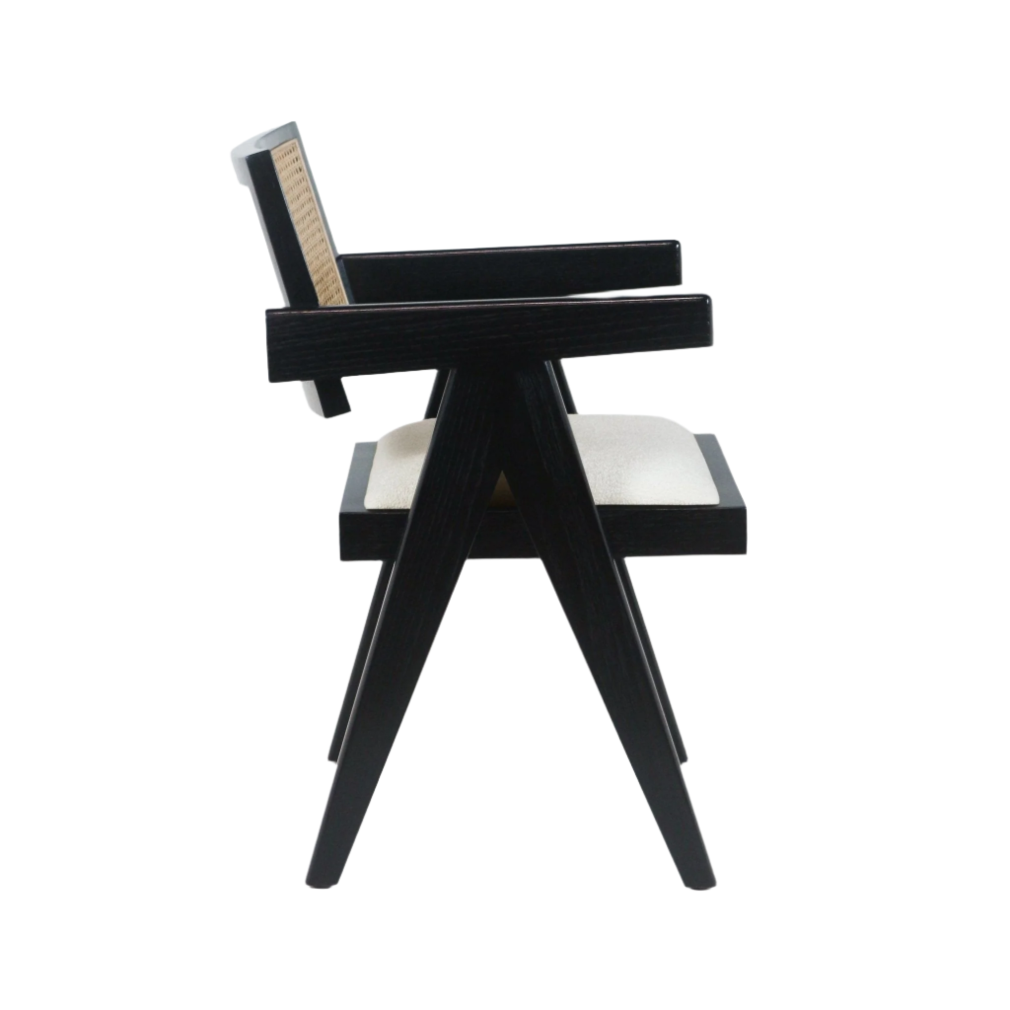 Side profile of a mid-century modern dining chair with a black-stained wood frame, woven cane back, light beige upholstered seat, angular splayed legs and integrated armrests.