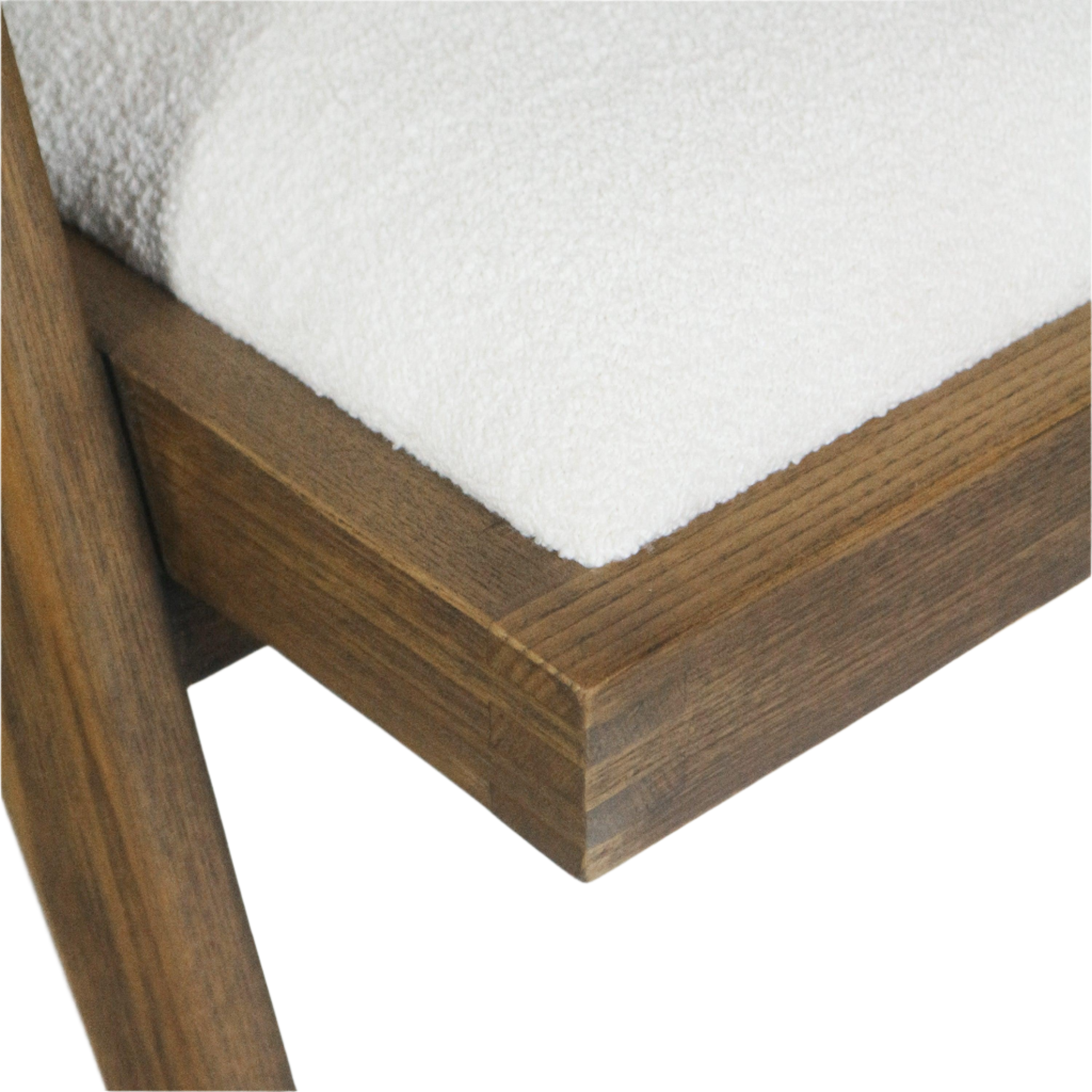 Close-up of a warm brown natural wood chair frame corner with a white boucle upholstered seat cushion, showing wood grain, joinery and the textured fabric surface.
