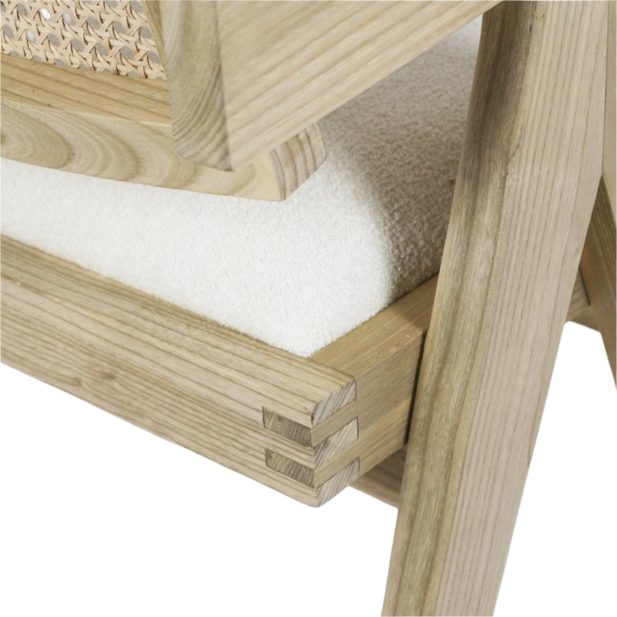 Close-up of a natural wood dining chair frame showing woven cane back, visible finger-joint joinery and an off-white boucle upholstered seat cushion.