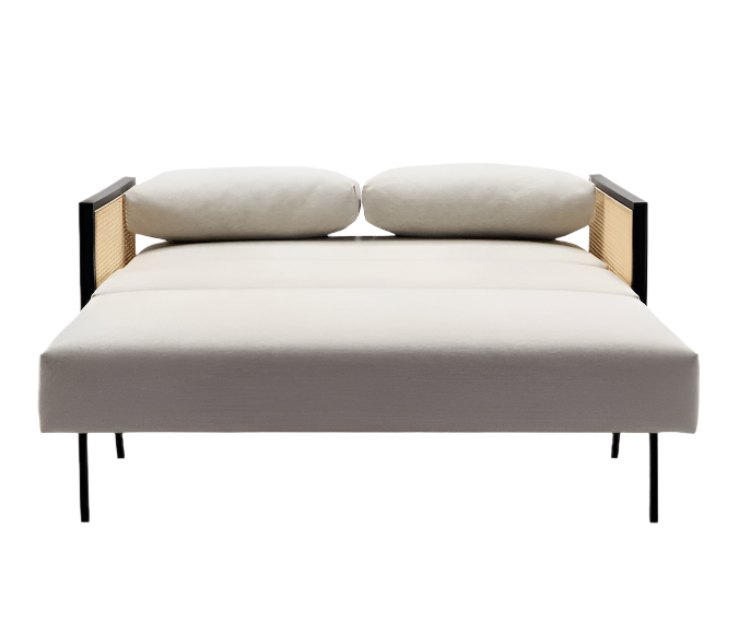 Front view of a modern beige upholstered sofa bed with black metal legs, wooden arms featuring cane panels, and two rounded back cushions, shown in the flattened bed position on a white background.
