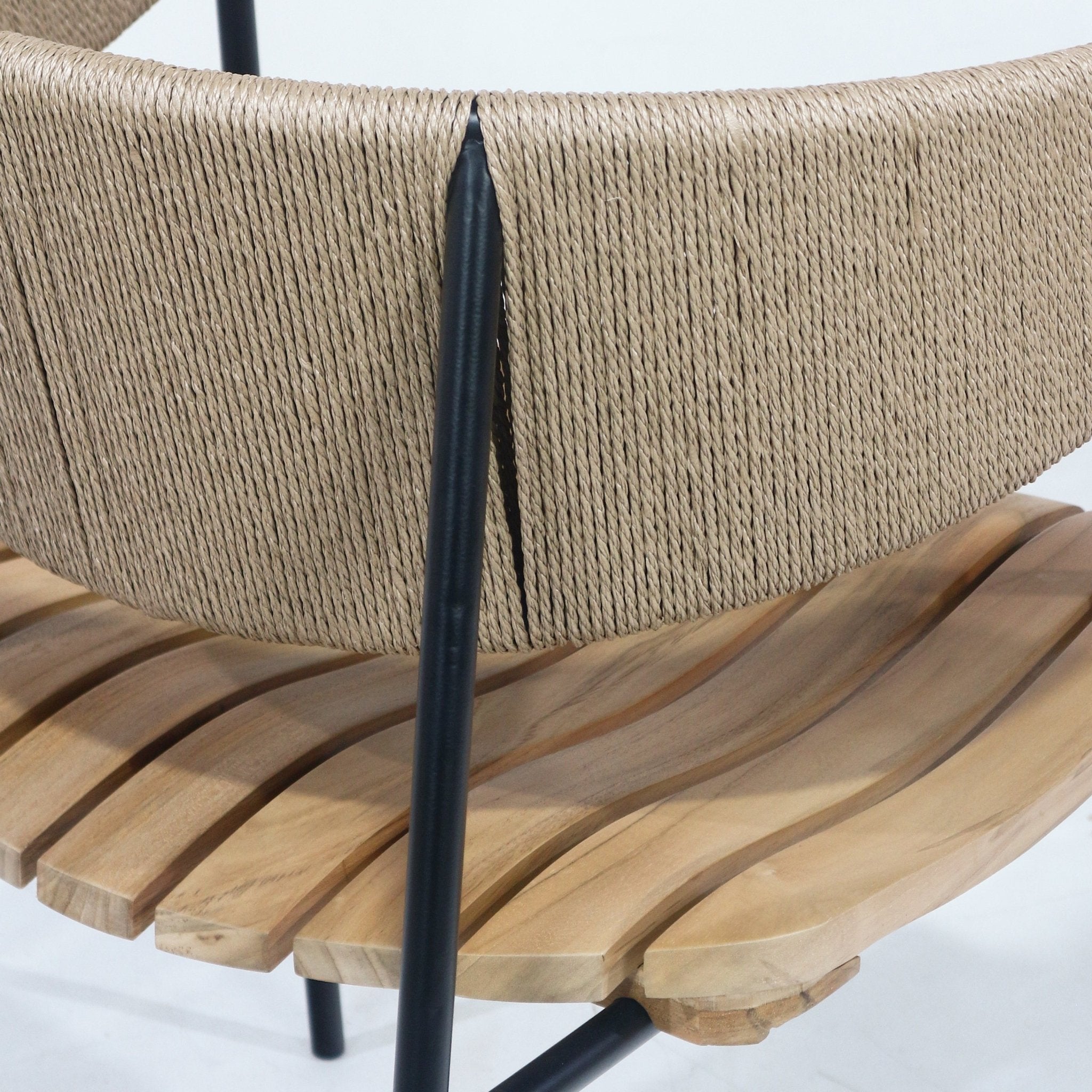 Close-up of a dining chair showing a natural teak slatted seat with curved slats, tightly woven beige rush webbing back, and a matte black metal leg and support.
